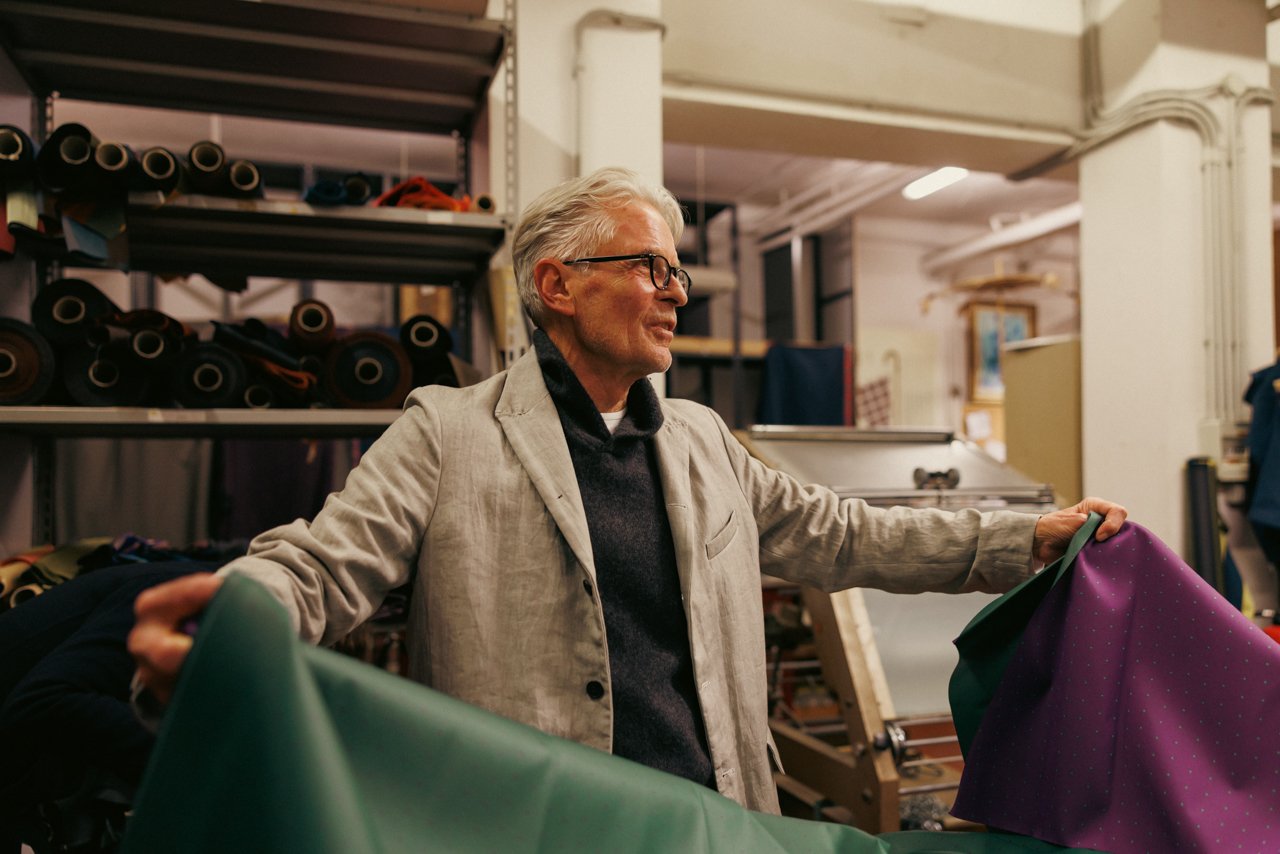 Older gentleman client inspecting a large bolt of green umbrella fabric.