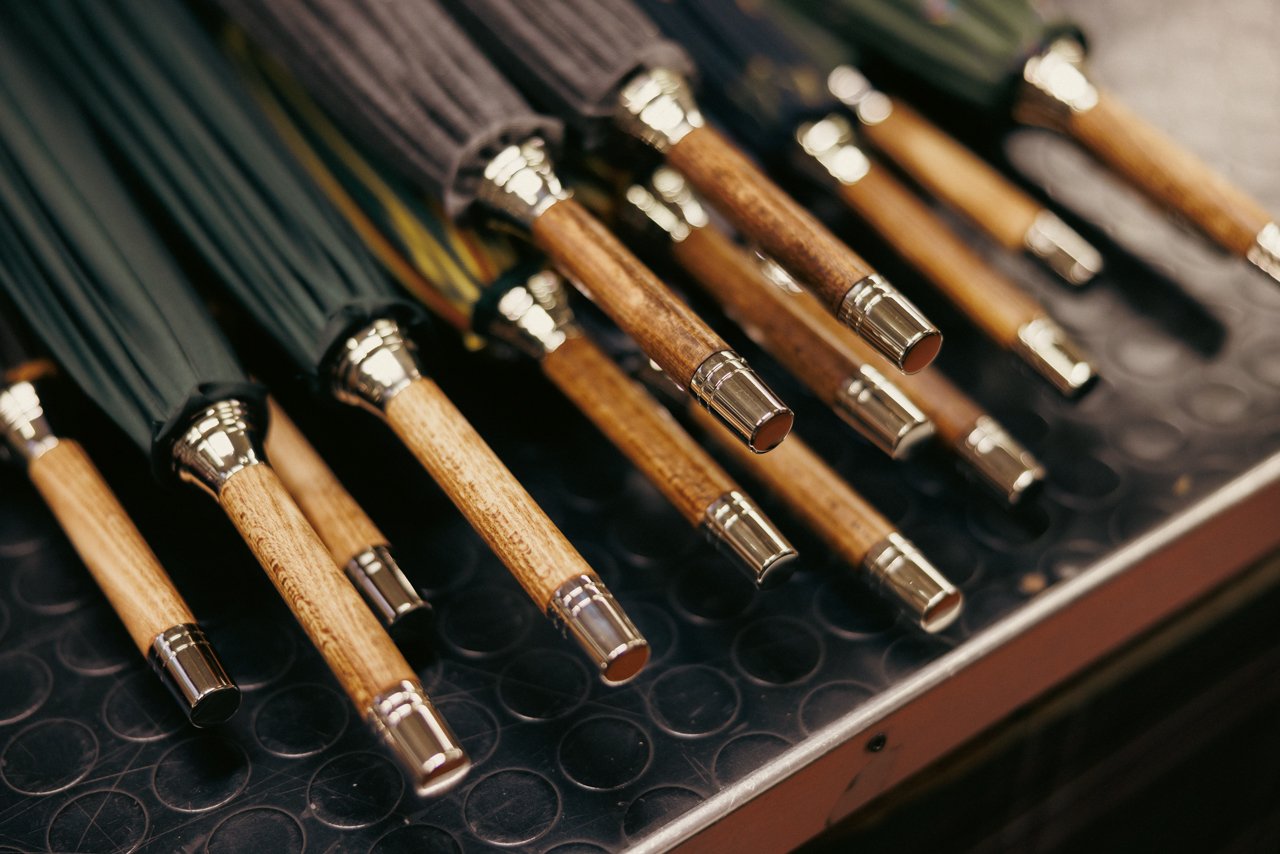 Tray filled with neatly arranged, finished umbrella handles featuring textured wood grips and metal accents.