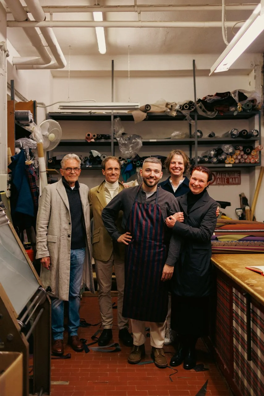 Group portrait featuring Francesco Maglia (center, in apron) with colleagues and visitors inside the Maglia workshop.