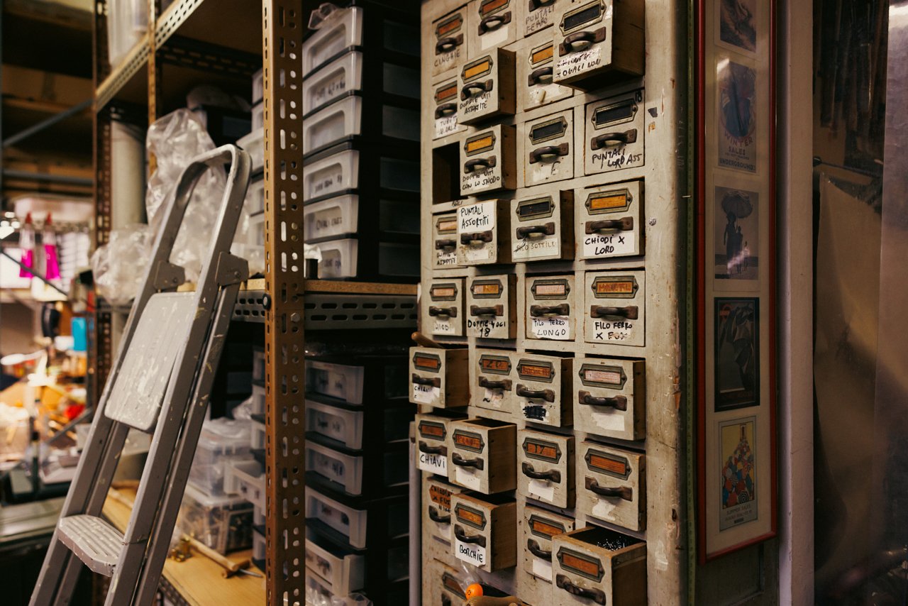 Storage shelves lined with numerous small, labelled boxes, presumably holding various umbrella parts and fittings.