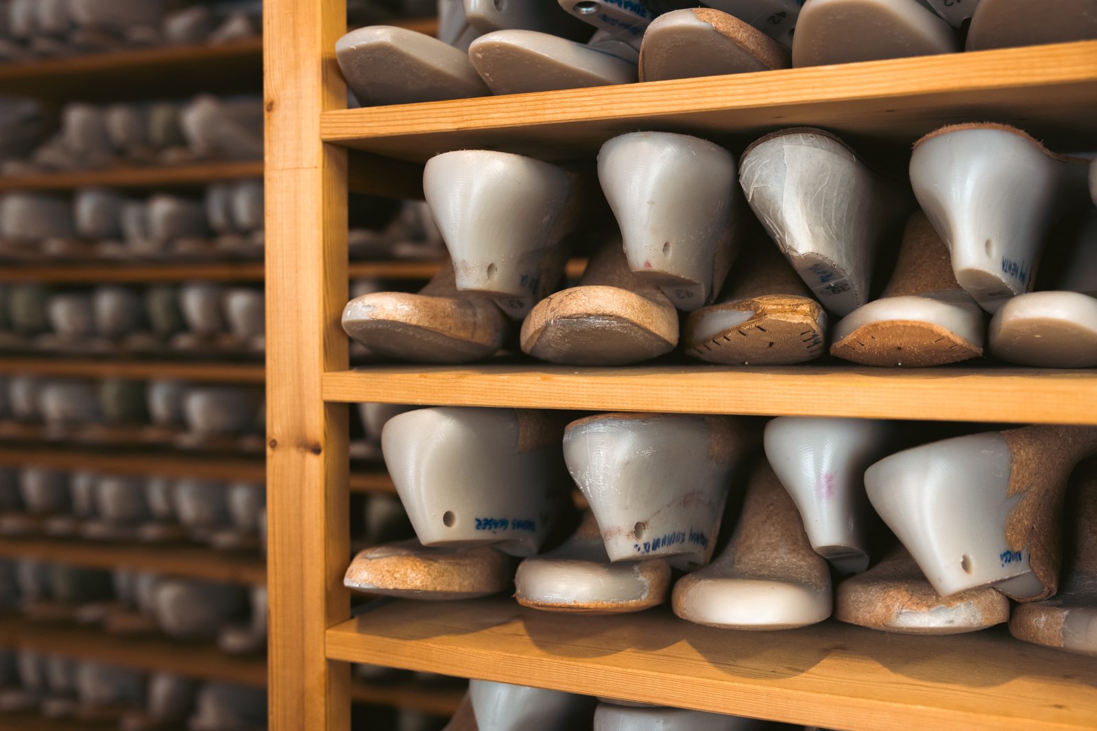 Shelves stocked with numerous wooden shoe lasts, essential tools for bespoke shoemaking in Vivian Saskia Wittmer's workshop.