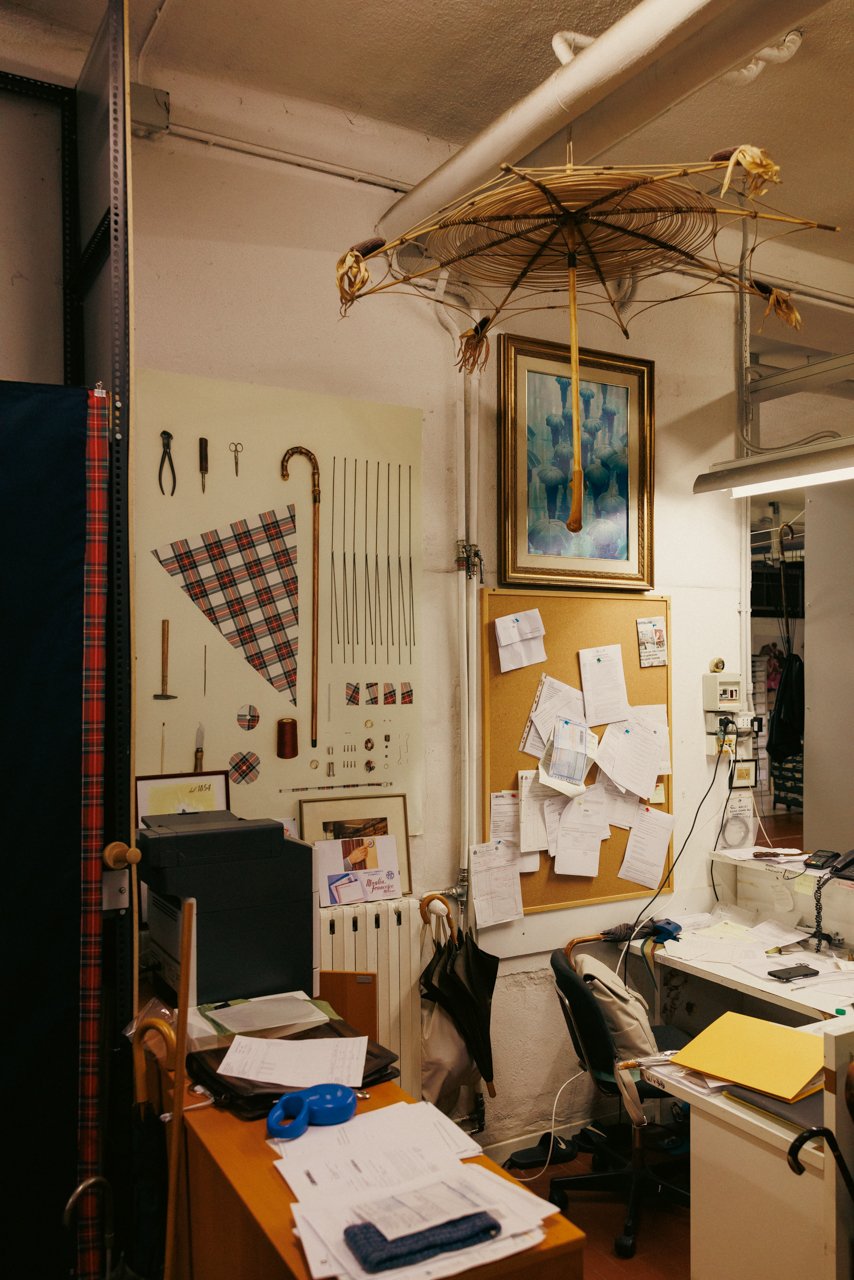 Corner workstation at Maglia showing tools, fabric samples, notes, and umbrella-themed decor.