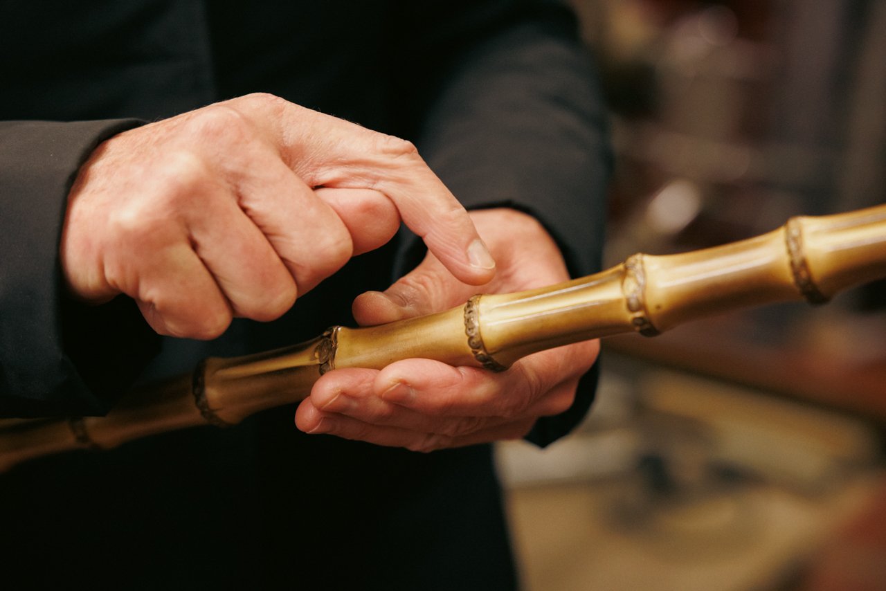 Close-up of hands examining the details of a natural bamboo umbrella handle.
