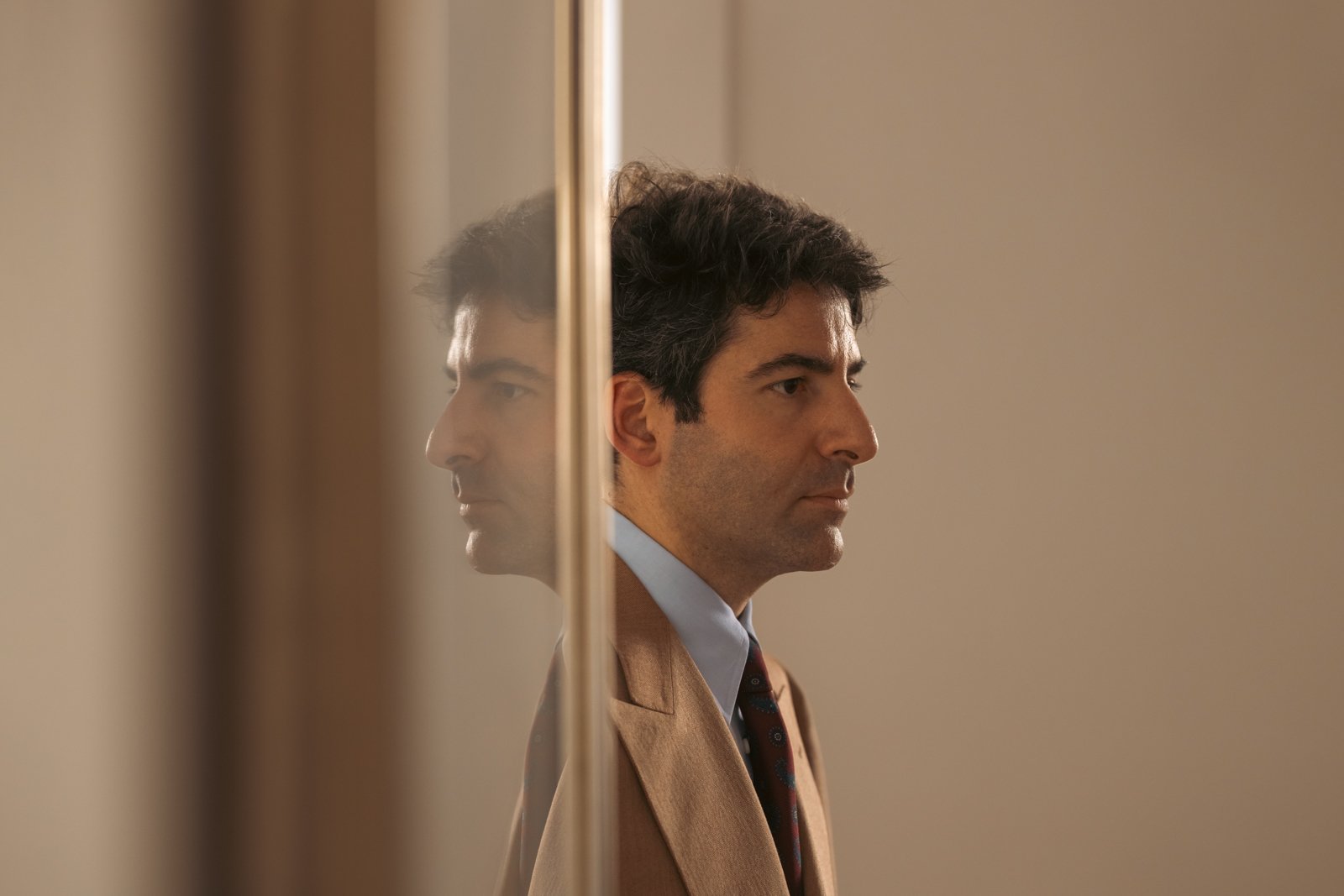Gianfrancesco Musella-Dembech in a bespoke suit mirrored by a reflective surface.