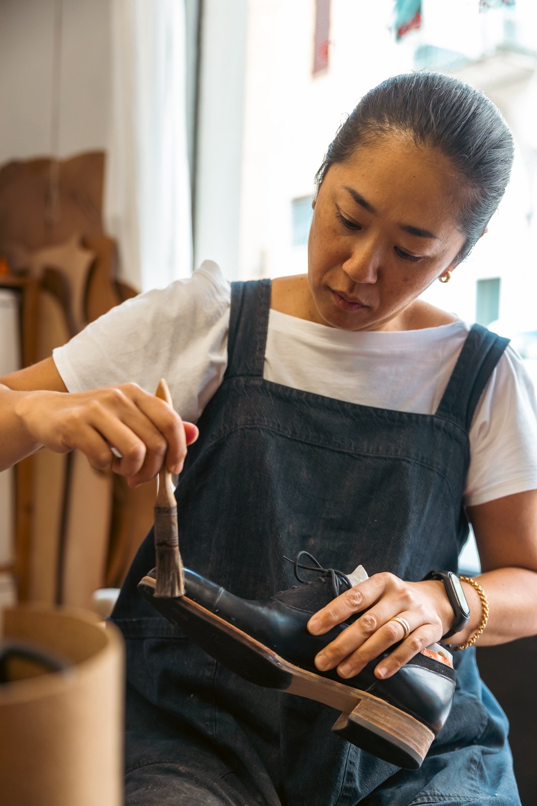 Shoemaker at Vivian Saskia Wittmer's workshop applying finish with a brush to the sole area of a bespoke shoe in the Florence atelier.