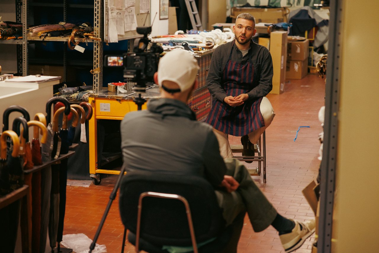 Francesco Maglia, wearing an apron, being filmed for an interview within the workshop setting.