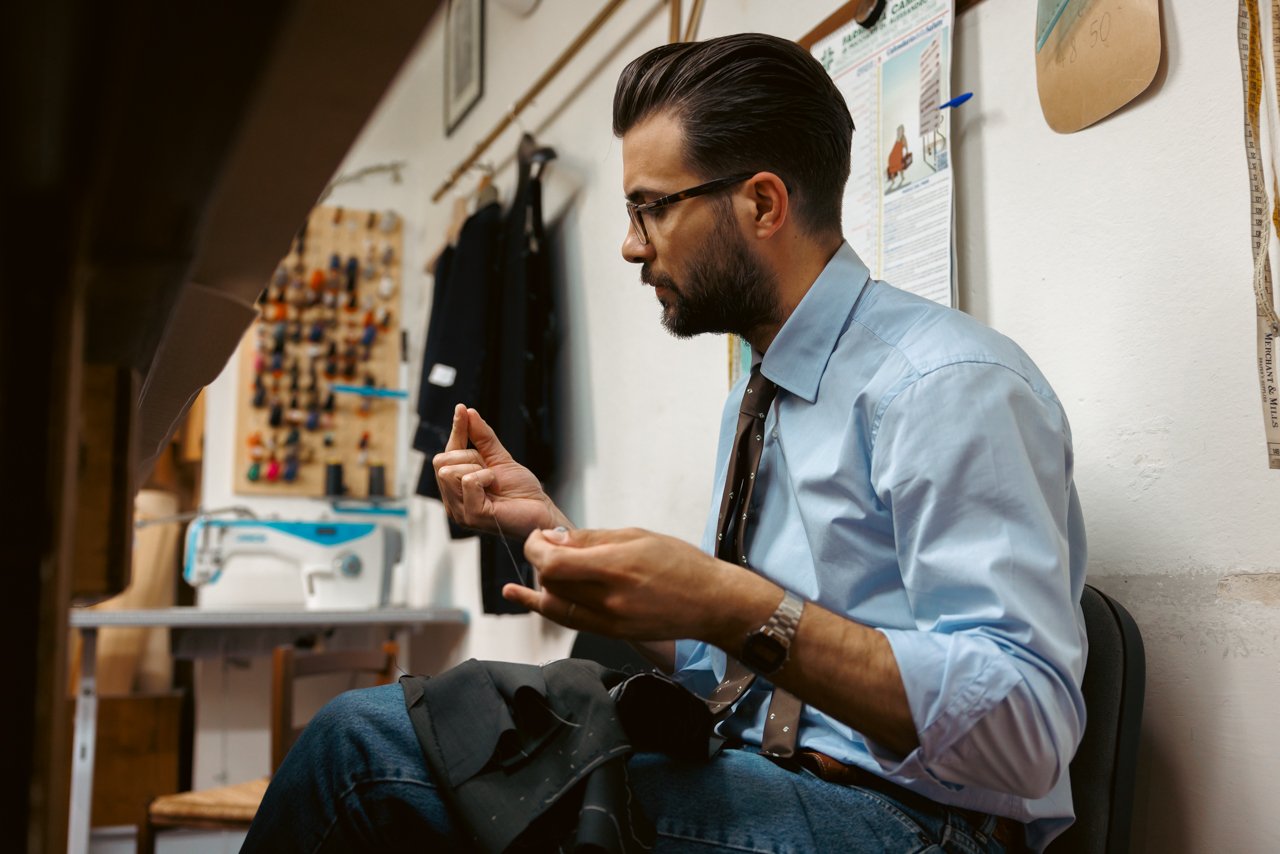 Liverano tailor sitting and meticulously hand-sewing a garment in the workshop.