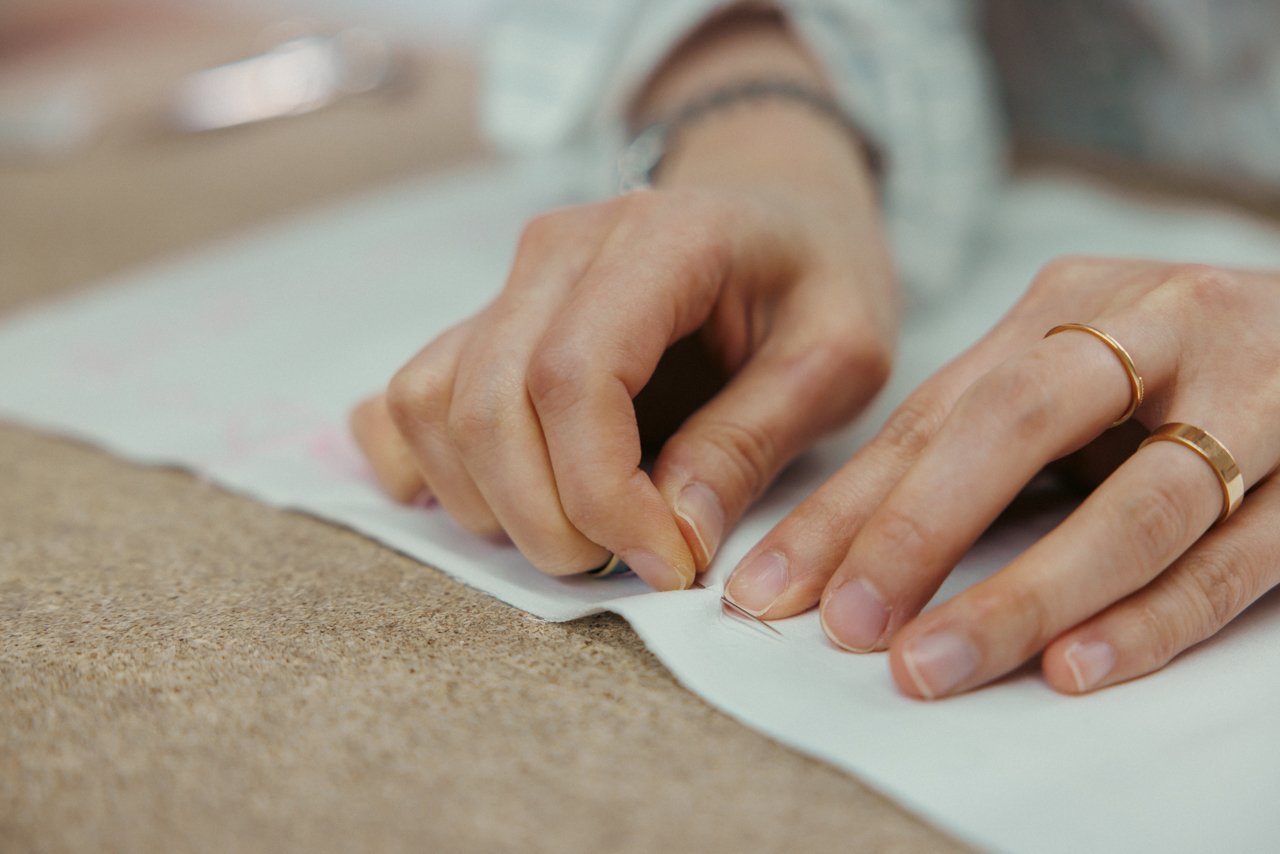 Detailed view of hands precisely pinning layers of fabric together.