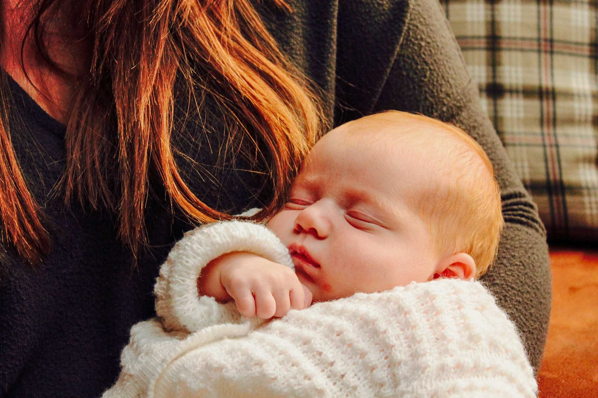 baby-in-white-cardigan-asleep-in-mothers-arms.jpg