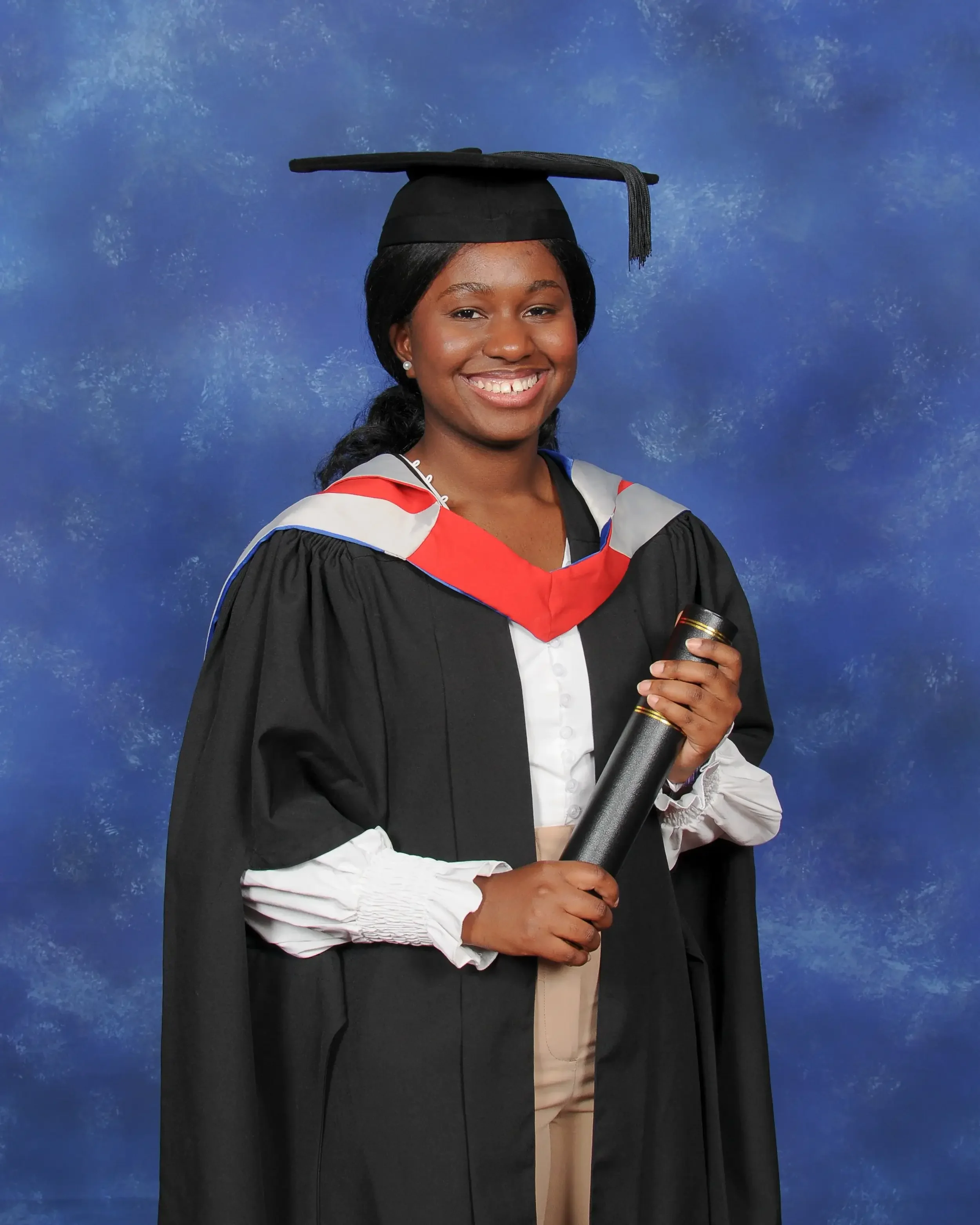 Young woman in graduation cap and gown holding a diploma against a blue textured background.