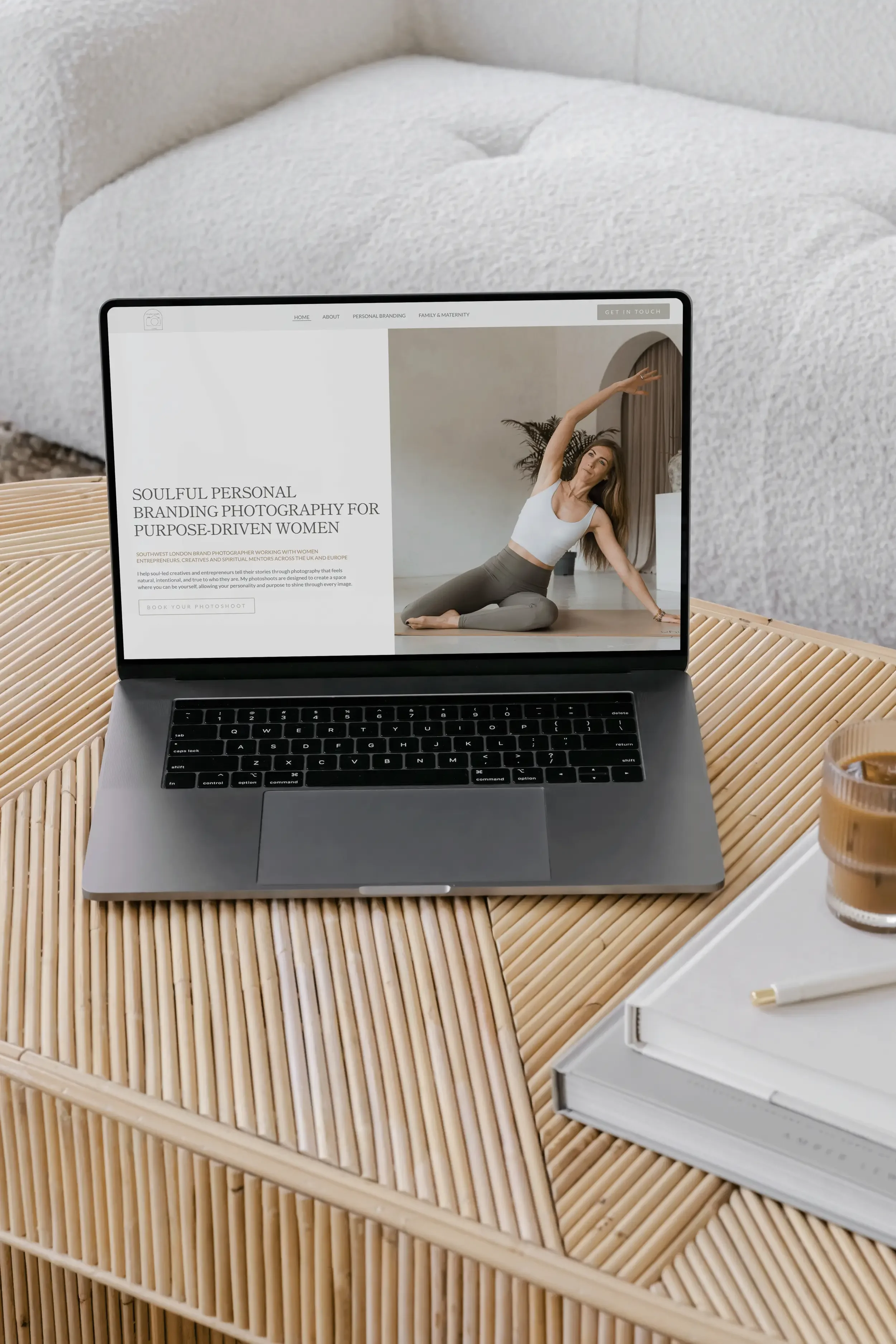 A laptop on a wooden table displaying a website about personal branding photography for women, with a woman stretching in a yoga pose on the screen.