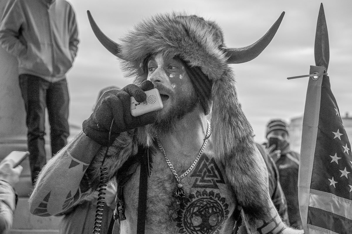 Amidst heightened tensions, the 'QAnon Shaman,' Jacob Chandler, urges a crowd of protesters outside the west side of the Capitol to go home. January 6, 2021, Washington D.C.