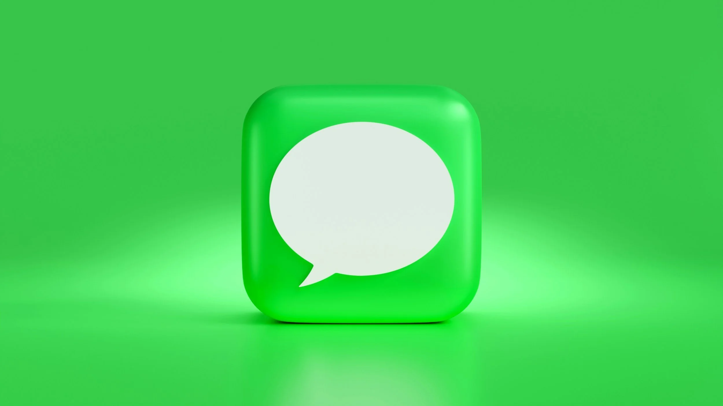 Close-up of a green icon with a white speech bubble, set against a green background.