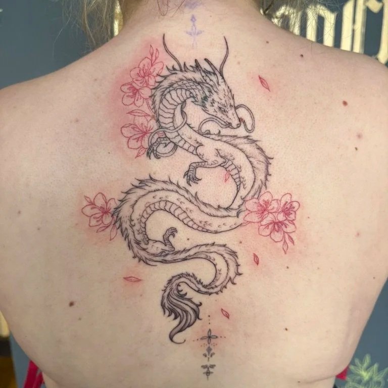 A tattoo of a dragon intertwined with cherry blossoms on a person's upper back.