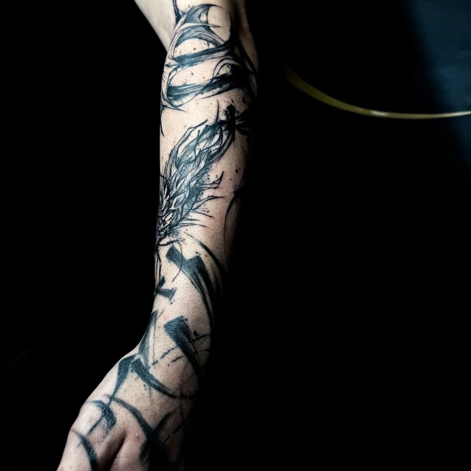 Black ink tattoo of a dragon on a person's arm with a dark background.