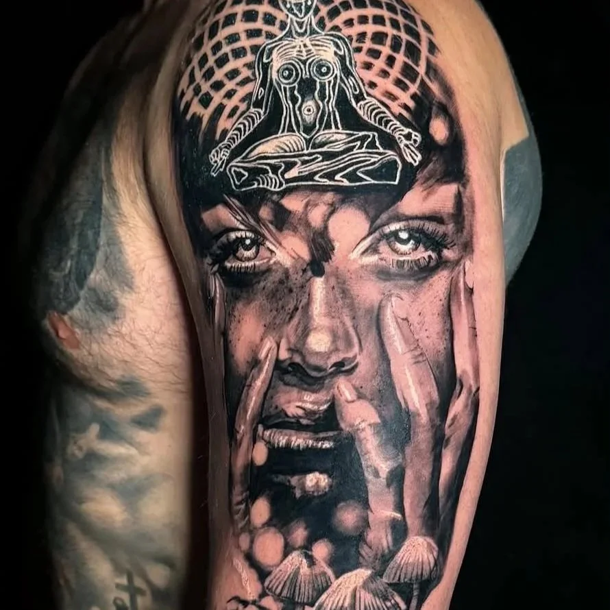 Black and gray tattoo portrait of a woman with tears, with detailed eyes and lips, featuring mushrooms at the bottom and a geometric pattern with abstract dog figure at the top.