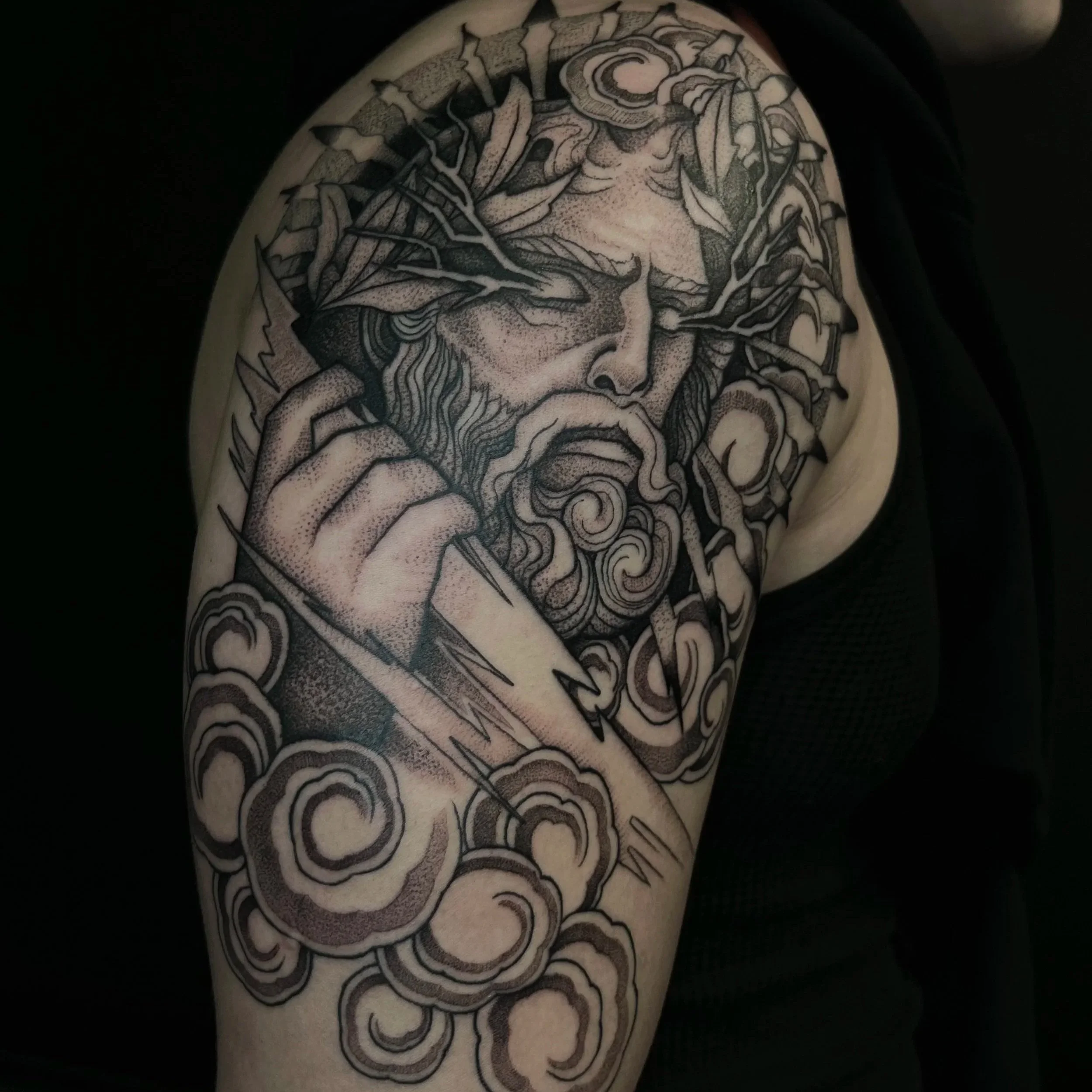 Black and gray tattoo of a bearded man with a crown of thorns on his head, holding a sword, surrounded by swirling clouds.