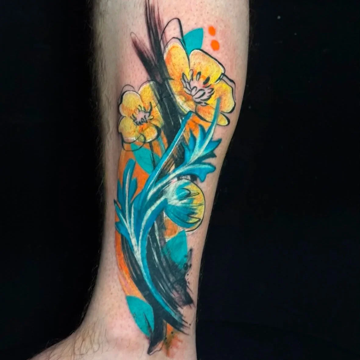 Abstract tattoo of yellow flowers with orange dots, blue leaves, and black brush strokes on a person's leg.