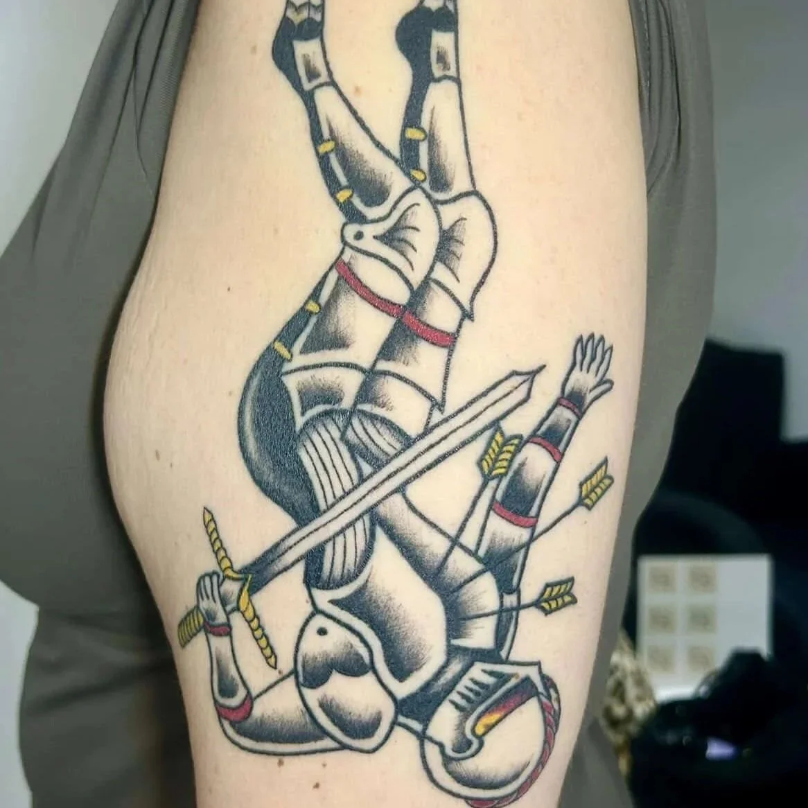 A tattoo of a knight falling with a broken sword, surrounded by arrows, next to a Spartan helmet.