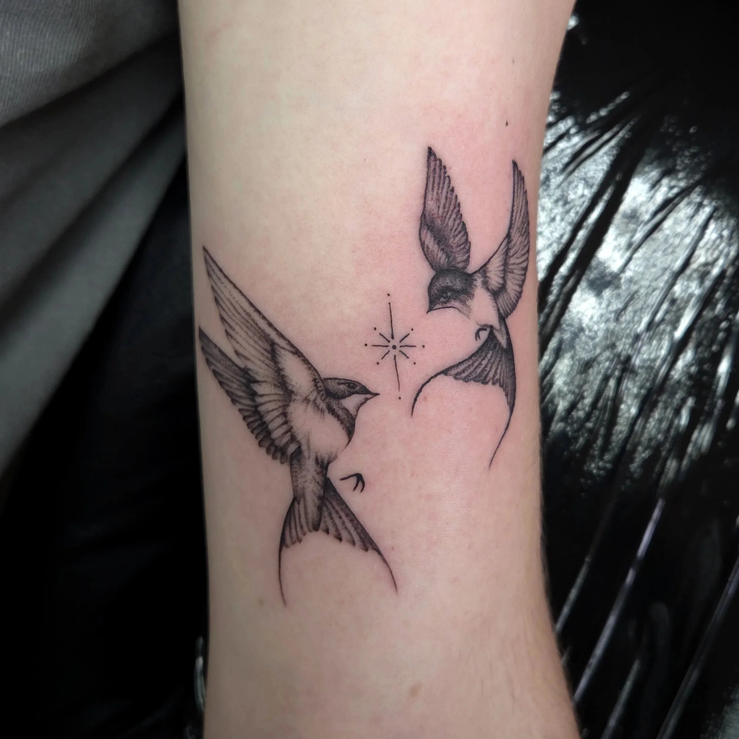 Tattoo of two flying birds with a small star and dotted line between them.