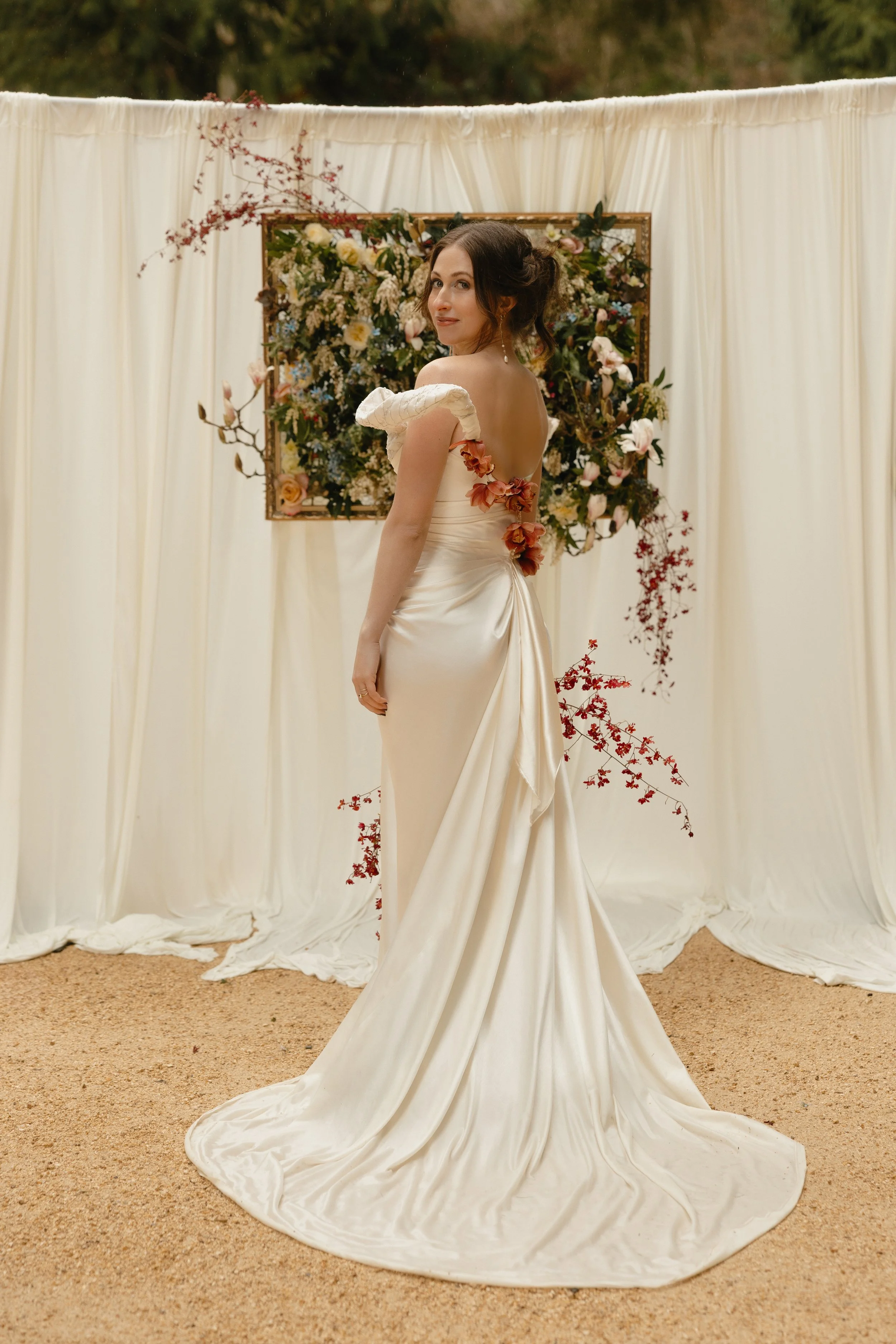 Luxurious silk wool is draped on a body sculpting strapless bridal gown featuring an architectural off the shoulder detail with embroidered poetry and a cascading train with a thigh high slit at Chateau Lill. Photography by Tori Osteraa.