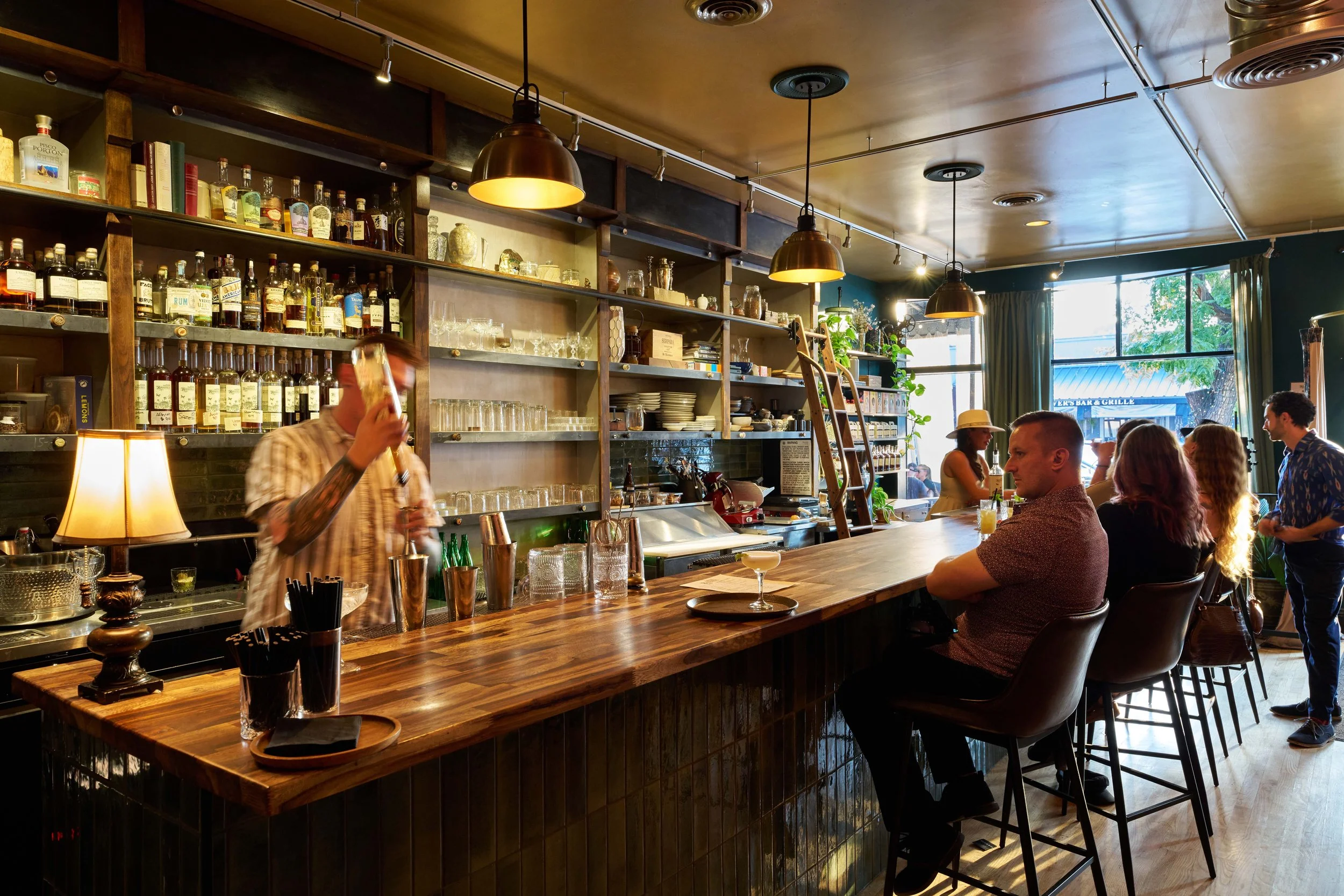 Guests gathering at Broderick’s warmly lit cocktail bar.