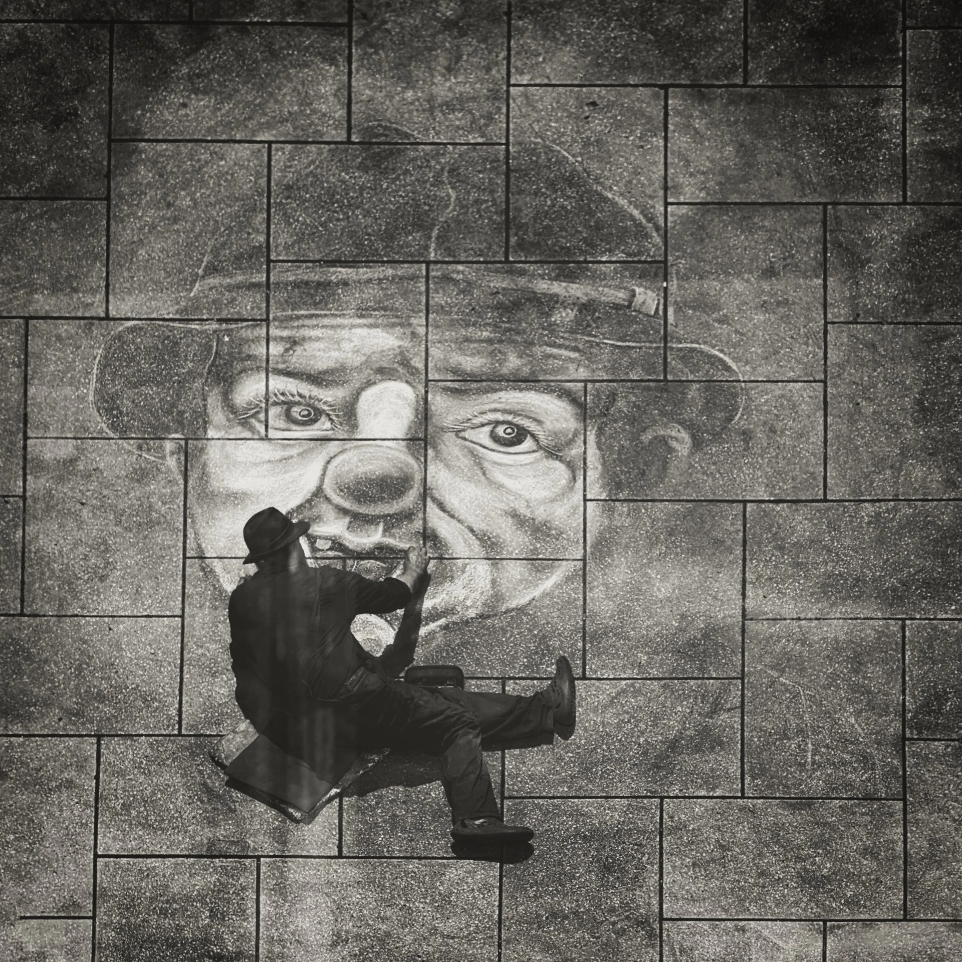 Street artist painting a mural of a woman's face on a tiled wall, with a man standing nearby.