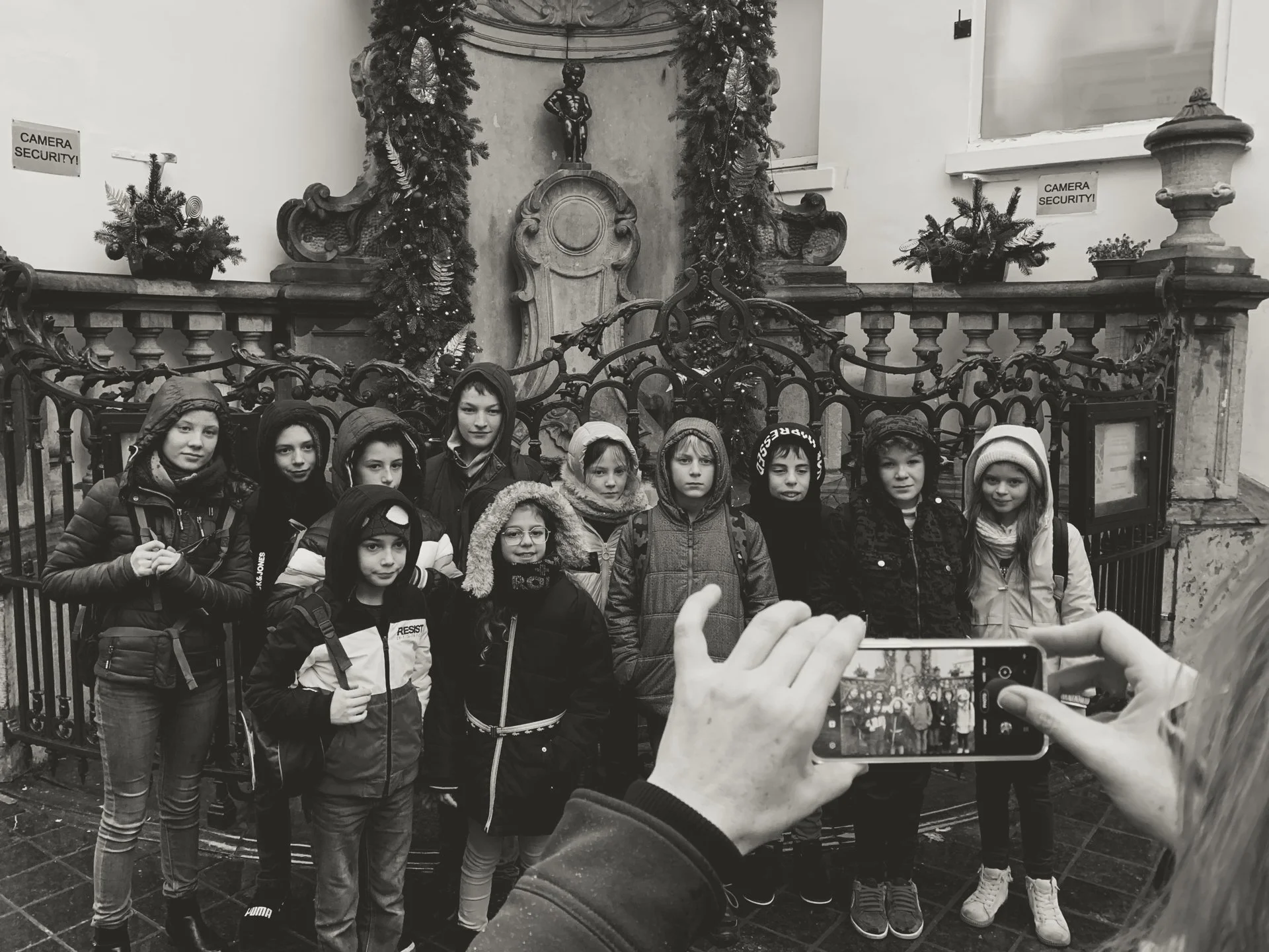 A group of children posing for a photo in front of a decorative church altar. Someone is taking a picture with a smartphone, capturing the moment.