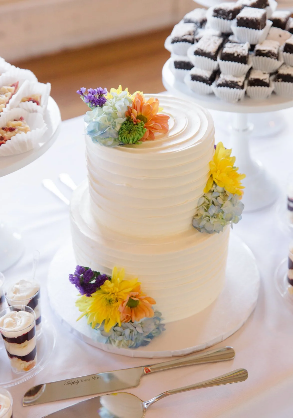 Two-tier white wedding cake with colorful flowers.