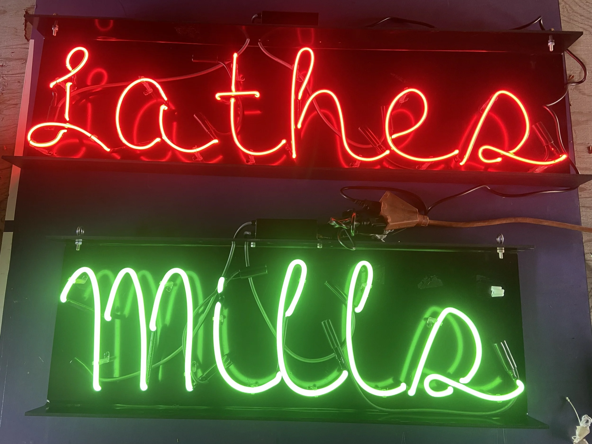 Red and Green neon signs with the word "Lathes" written in red, and the word "Mills" written in green underneath.