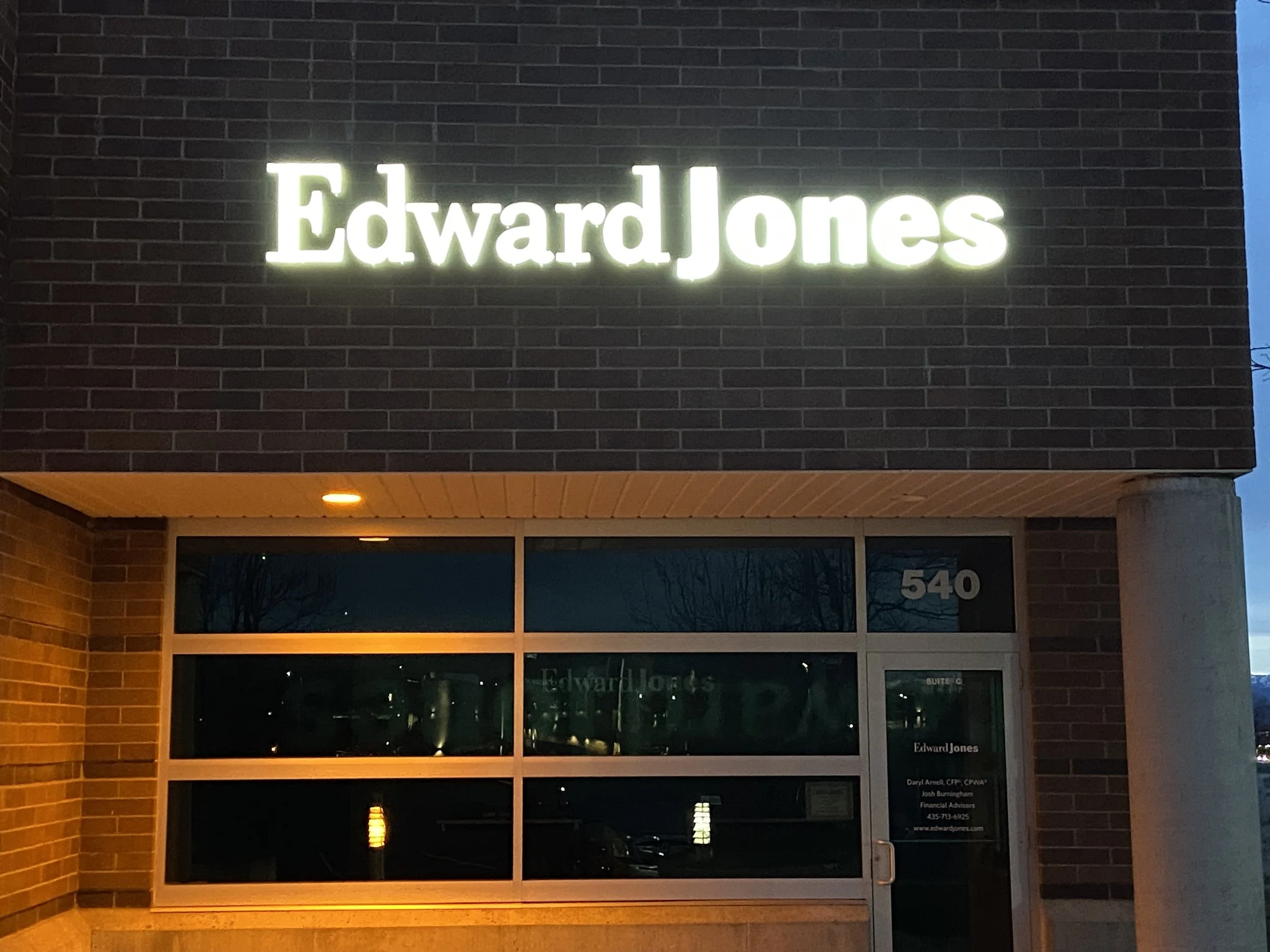 Illuminated sign displaying the name "Edward Jones" on a brick building exterior at dusk. LED retrofit
