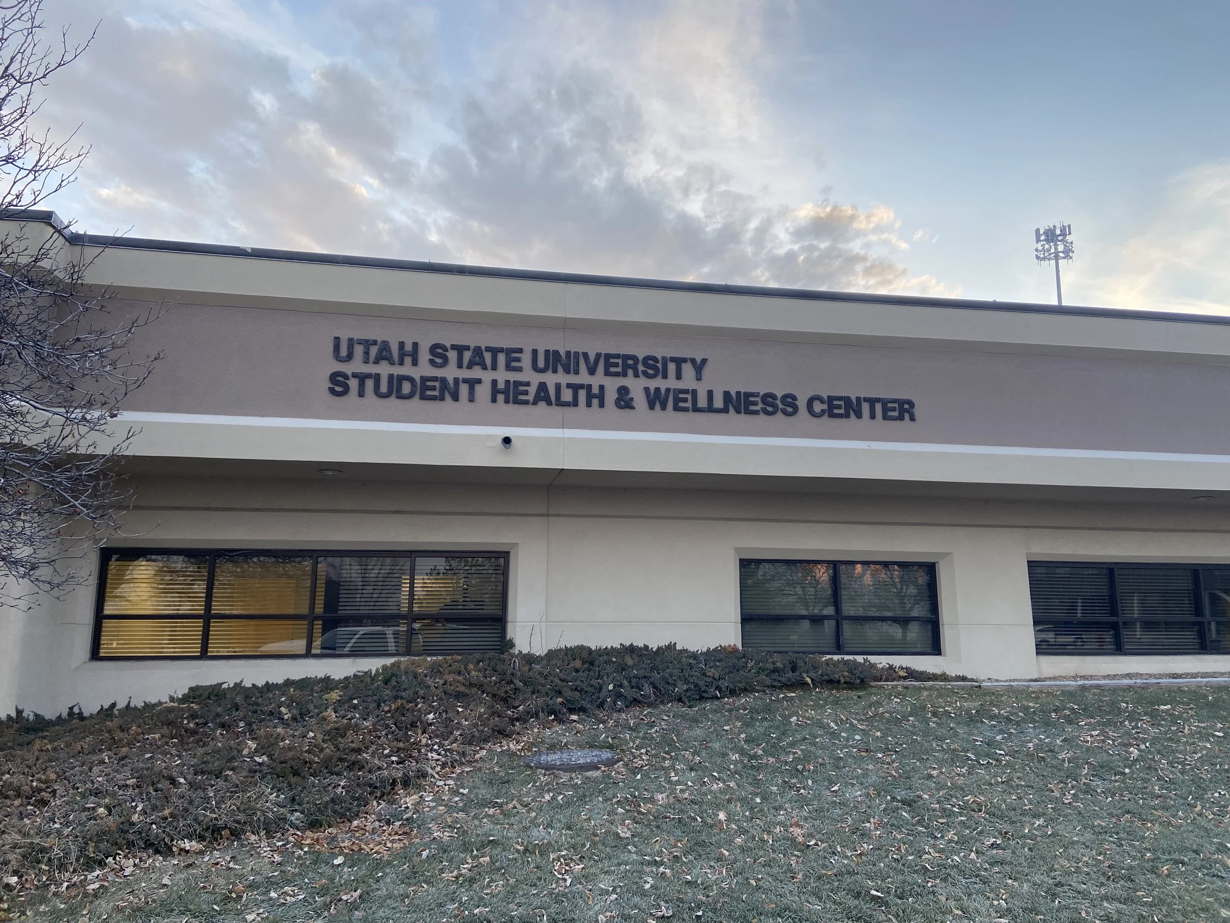 Exterior of the Utah State University Student Health & Wellness Center building with clouds in the sky.