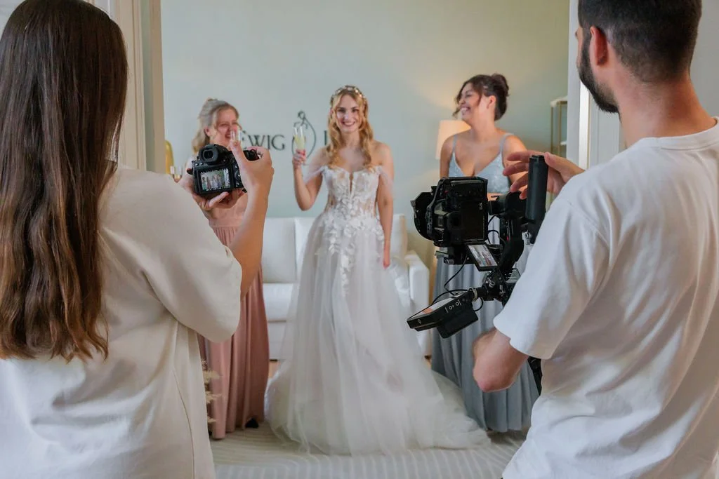 Eine Braut posiert mit Freundinnen während der Hochzeitsaufnahme, während zwei Videografen - Nico und Sofia von LoCrew Videos machen.