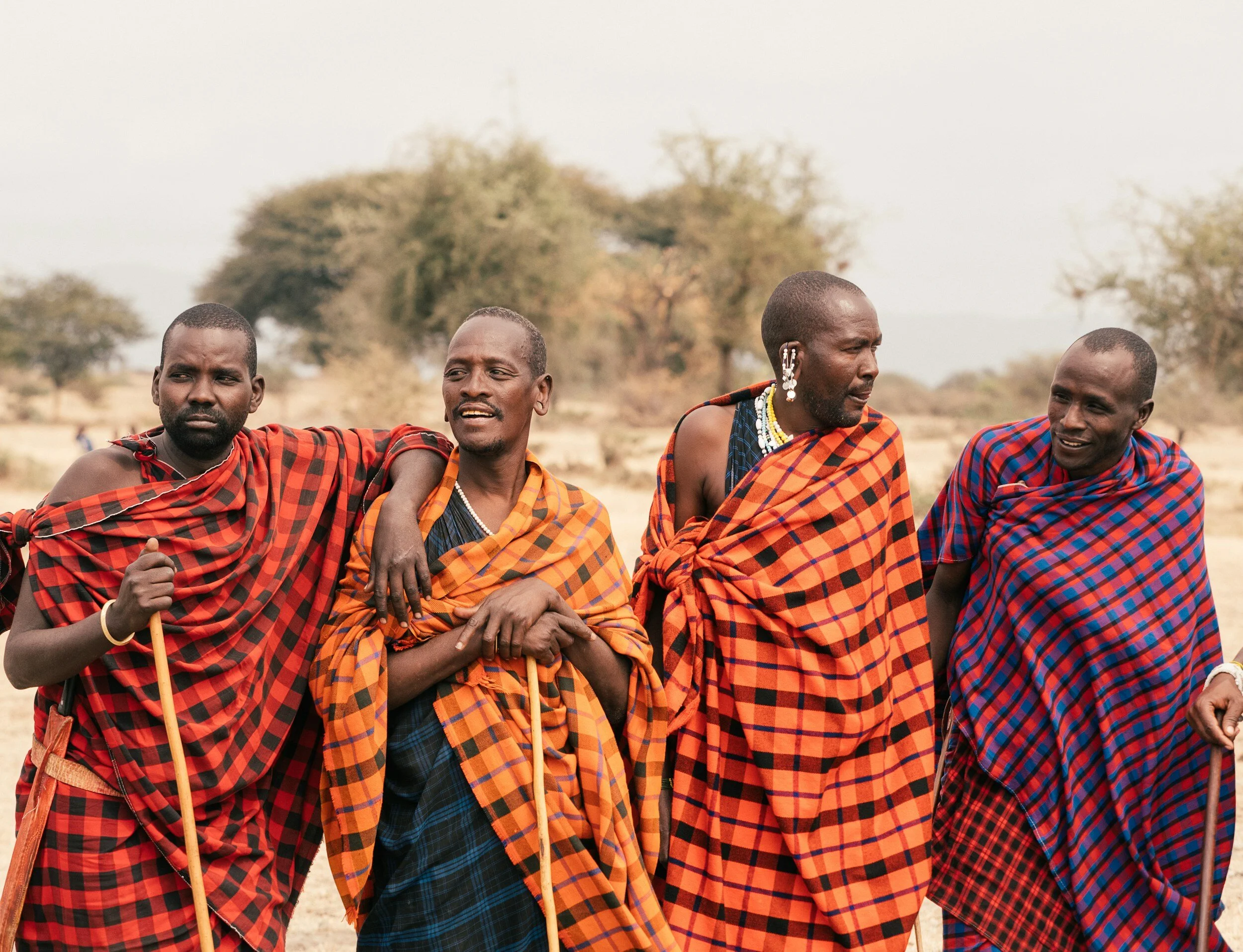 Maasai men with traditional cloth standing together casually and looking into the distance