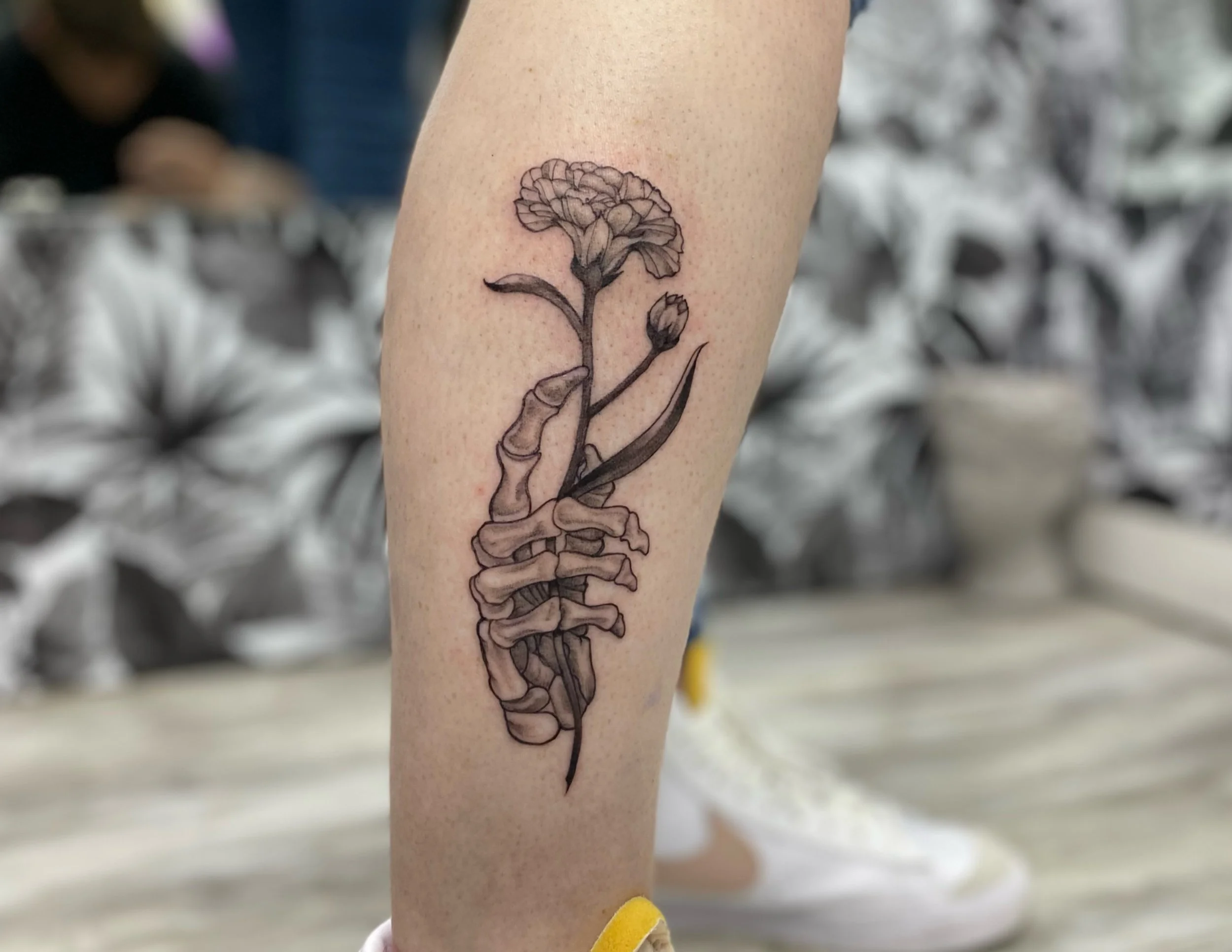 A tattoo of a human spine with a flower growing from the top on a person's arm.