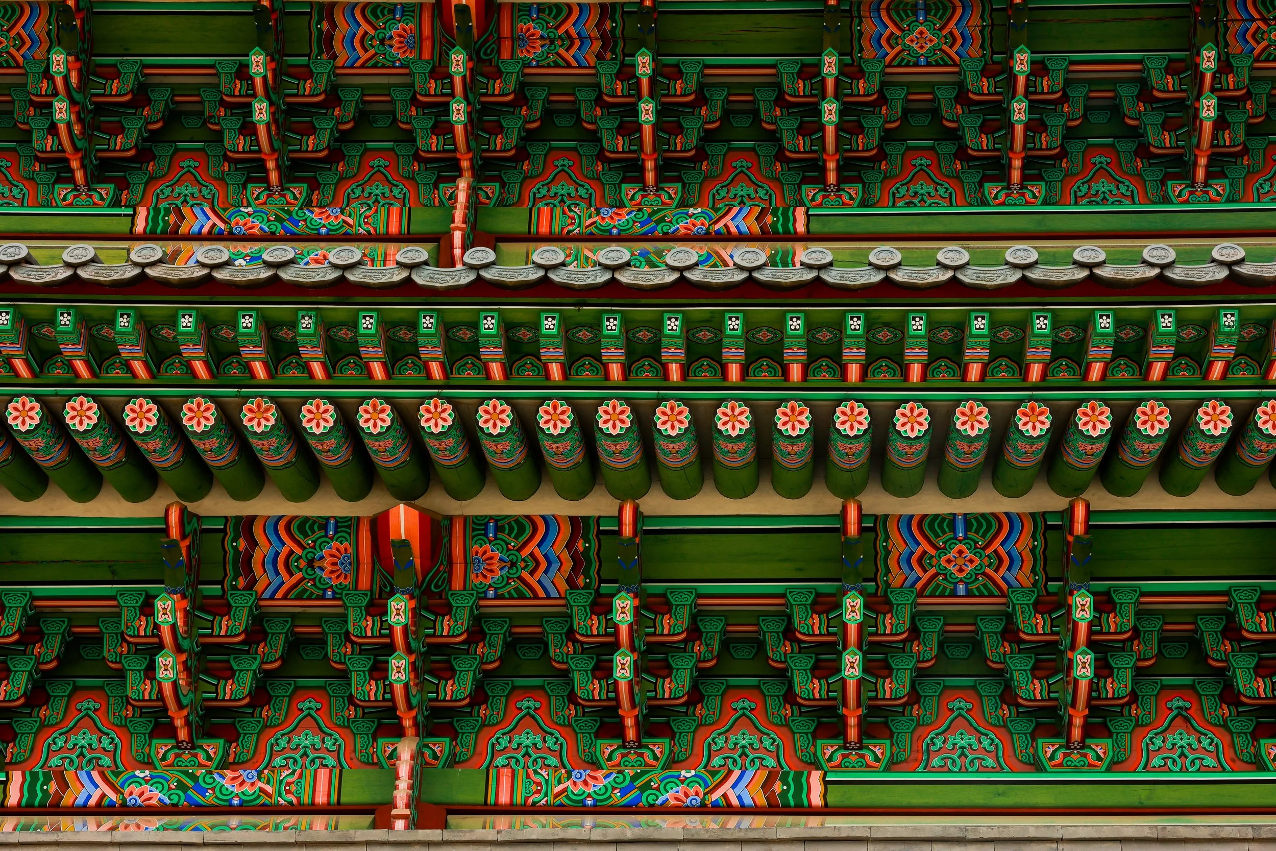 Colorful, ornate Traditional Korean building with intricate carvings and bright patterns in green, red, blue, and orange.