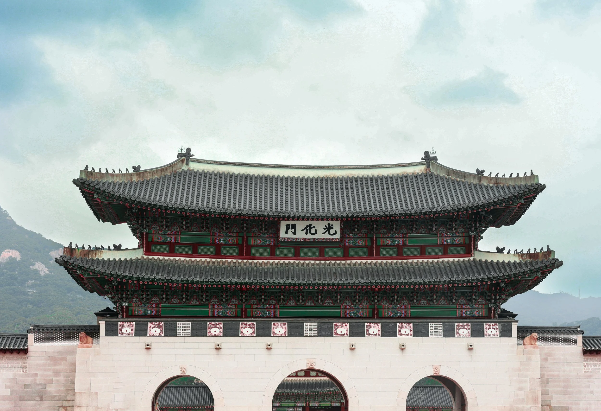 Traditional East Asian temple with ornate, curved roof and decorative details, with a mountain in the background.