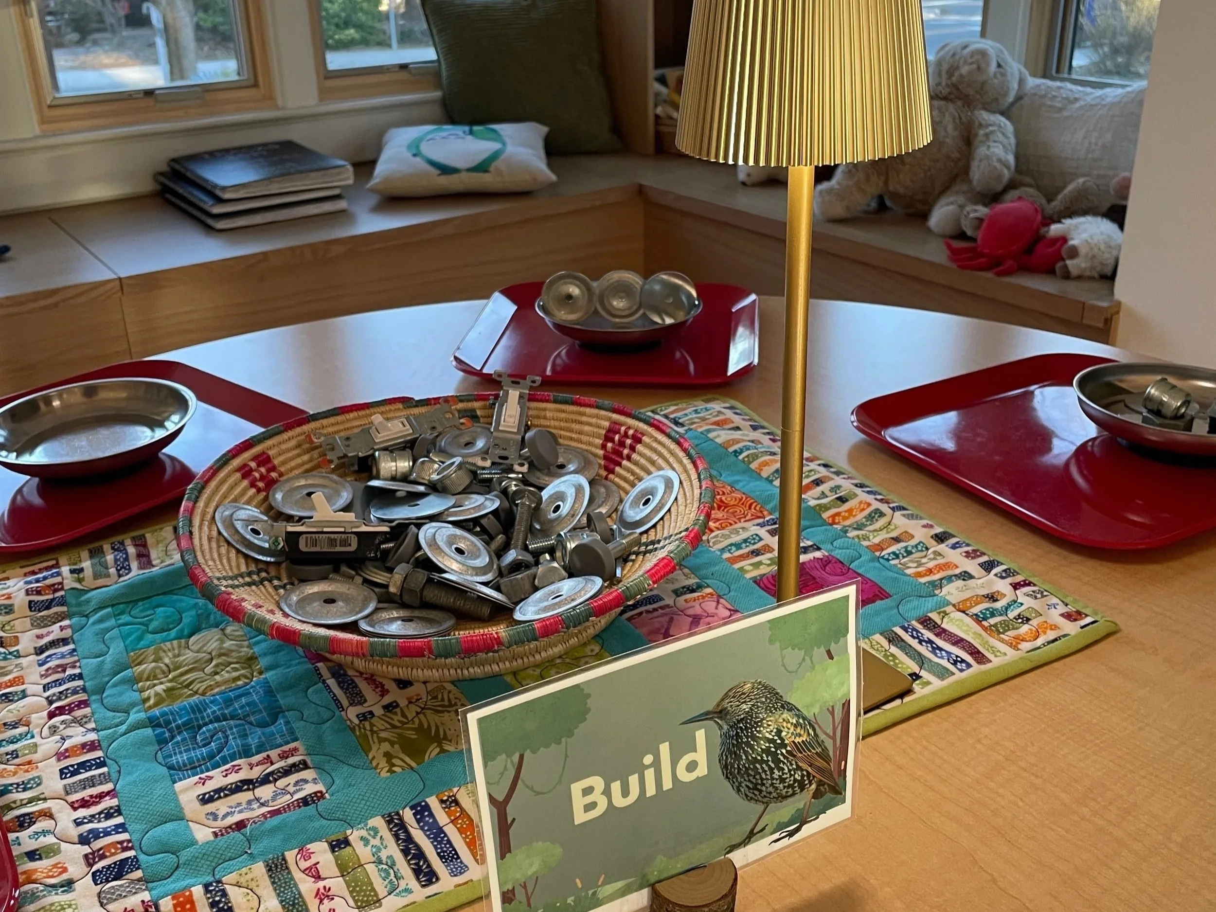 Child-led building exploration table with natural materials and soft lighting inviting children to design and construct in a play-based preschool environment