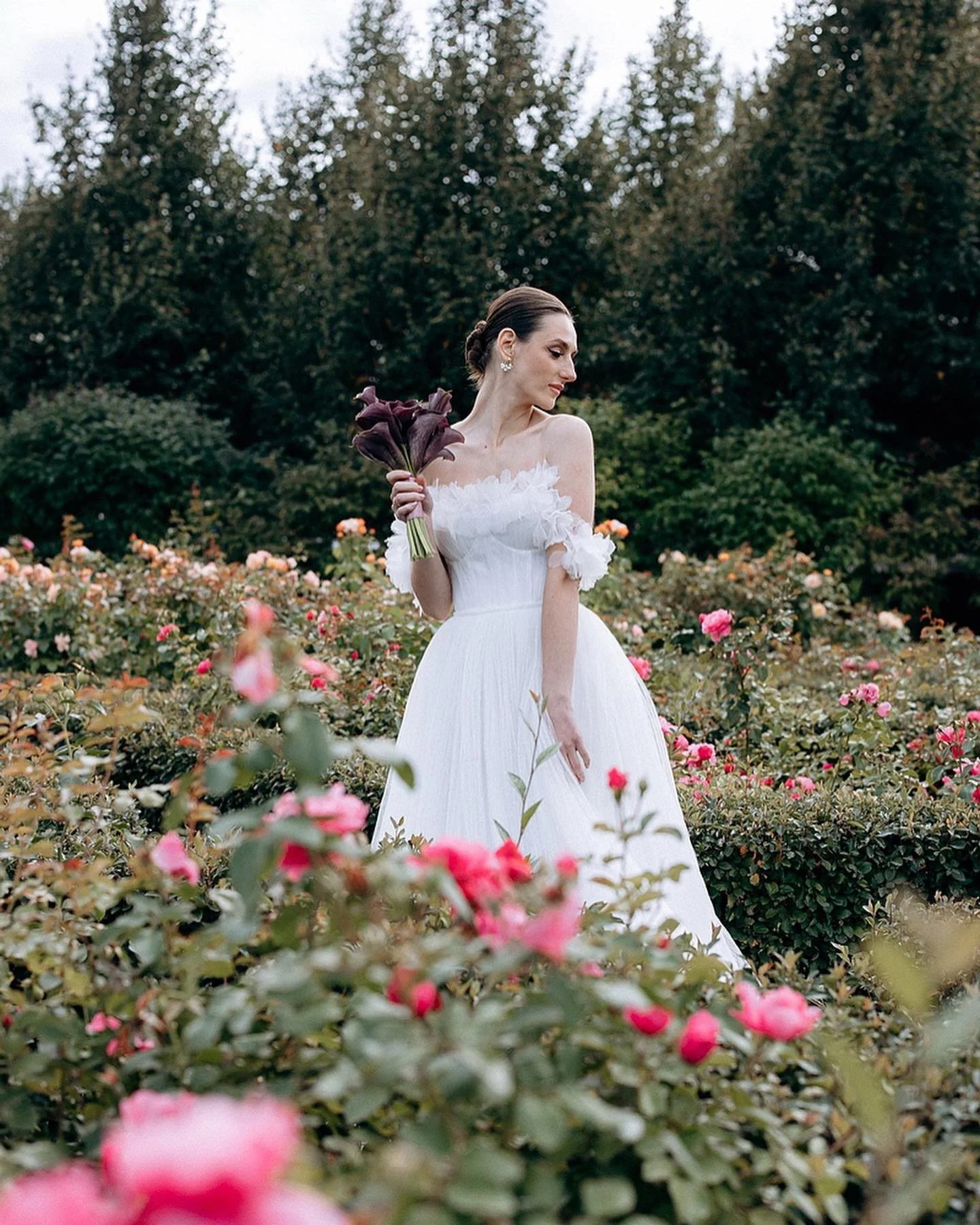Embrace the perfect blend of elegance and romance with the Charlotte gown by Lana Marinenko. This exquisite pleated wedding dress features a corset bustier adorned with delicate petal floral d&eacute;cor, optional long sleeves, and a voluminous skirt