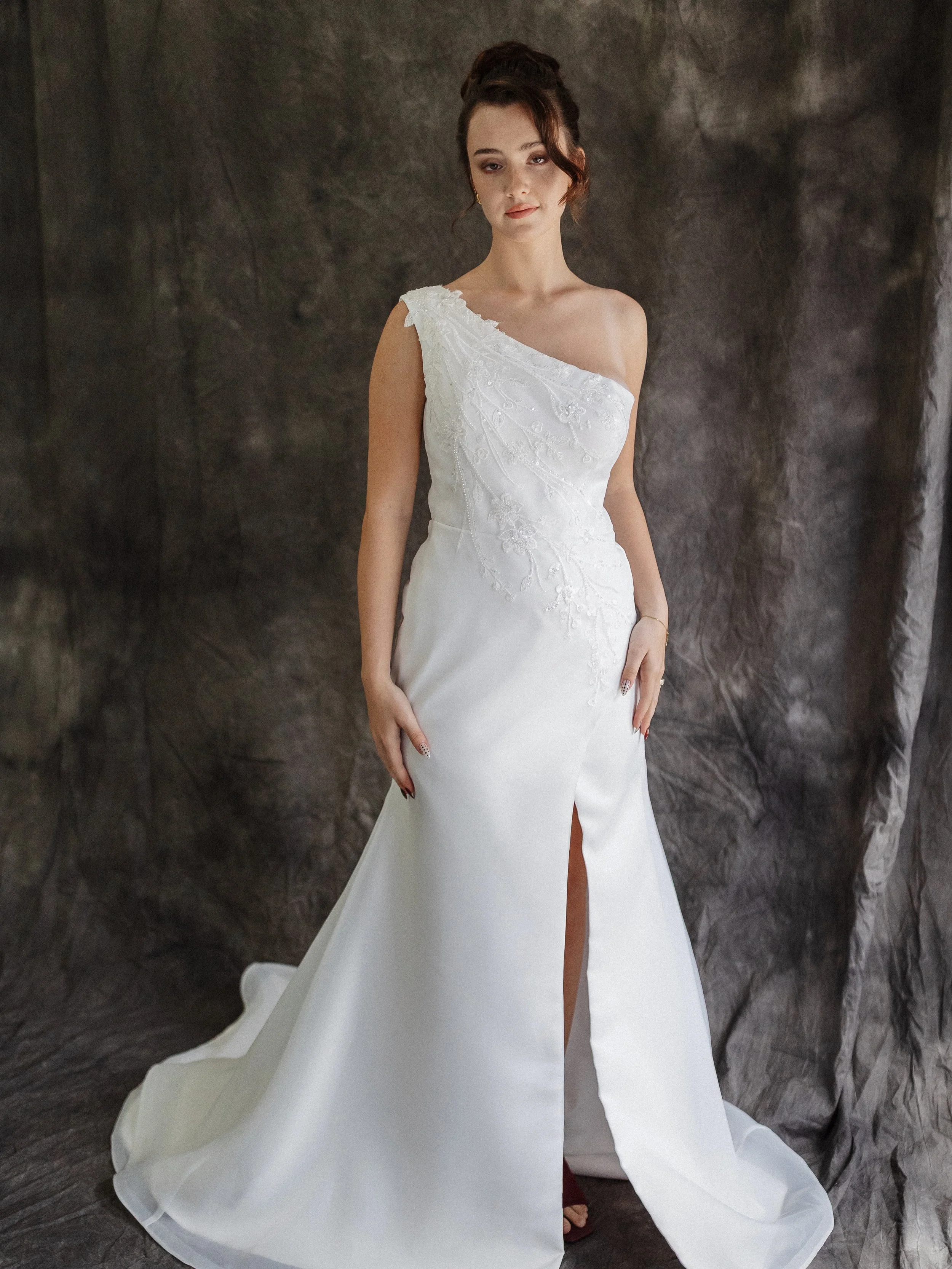 The Positano Wedding Gown: Modern Elegance with a Touch of Allure.

Step into timeless beauty with The Positano, a refined one-shoulder wedding dress designed for the bride who seeks effortless sophistication and a hint of daring charm. Perfect for m