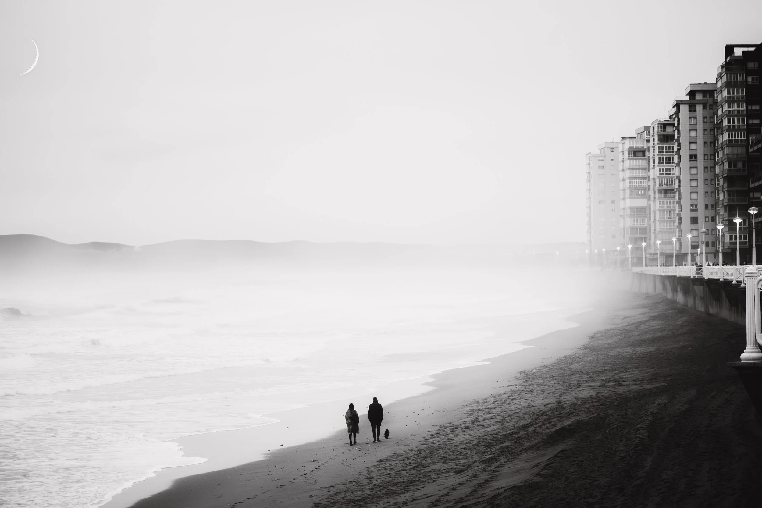 Personas caminando por la playa de Salinas en un día nublado, edificios al fondo, luna visible en el cielo. Imagen en blanco y negro.