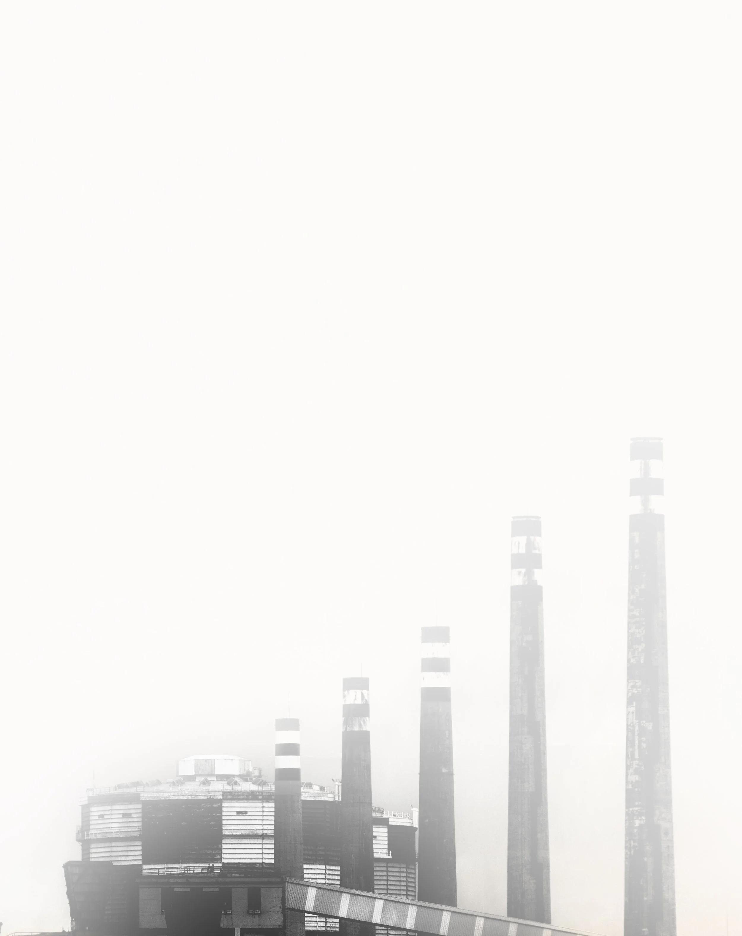 Edificio industrial con chimeneas altas en un día nublado.