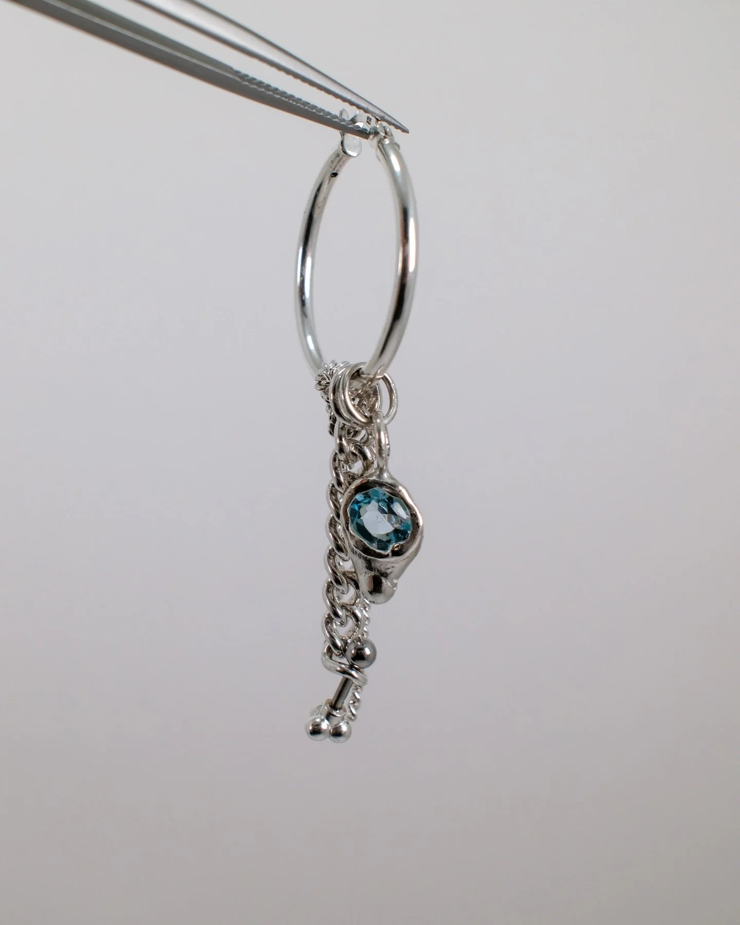 Freshly dropped hoop now on the web-store. 

Vincent, a 25mm hinged hoop. With different sized curb chains and a molten sky blue topaz.