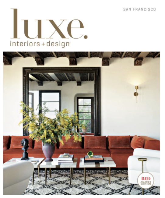Cover of Luxe Interiors + Design magazine featuring a modern living room with a red sectional sofa, a large floral arrangement, and a patterned area rug.