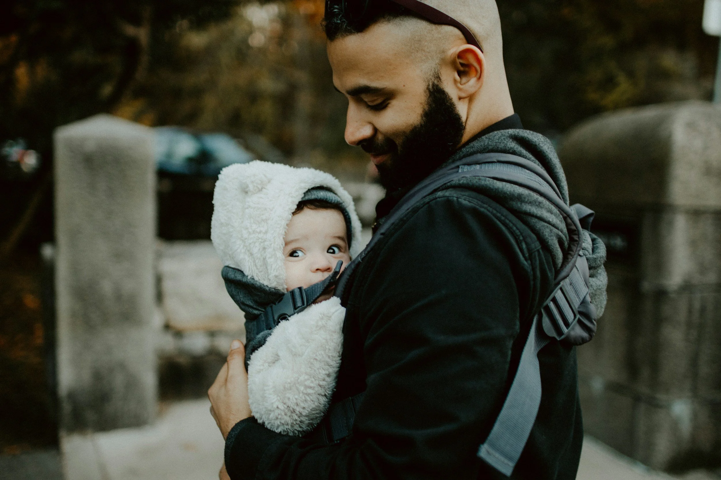 Image of a father outside with their baby in a wearable baby carrier in the tips for travelling with baby in a post about best places to travel with a baby in Kansas City.