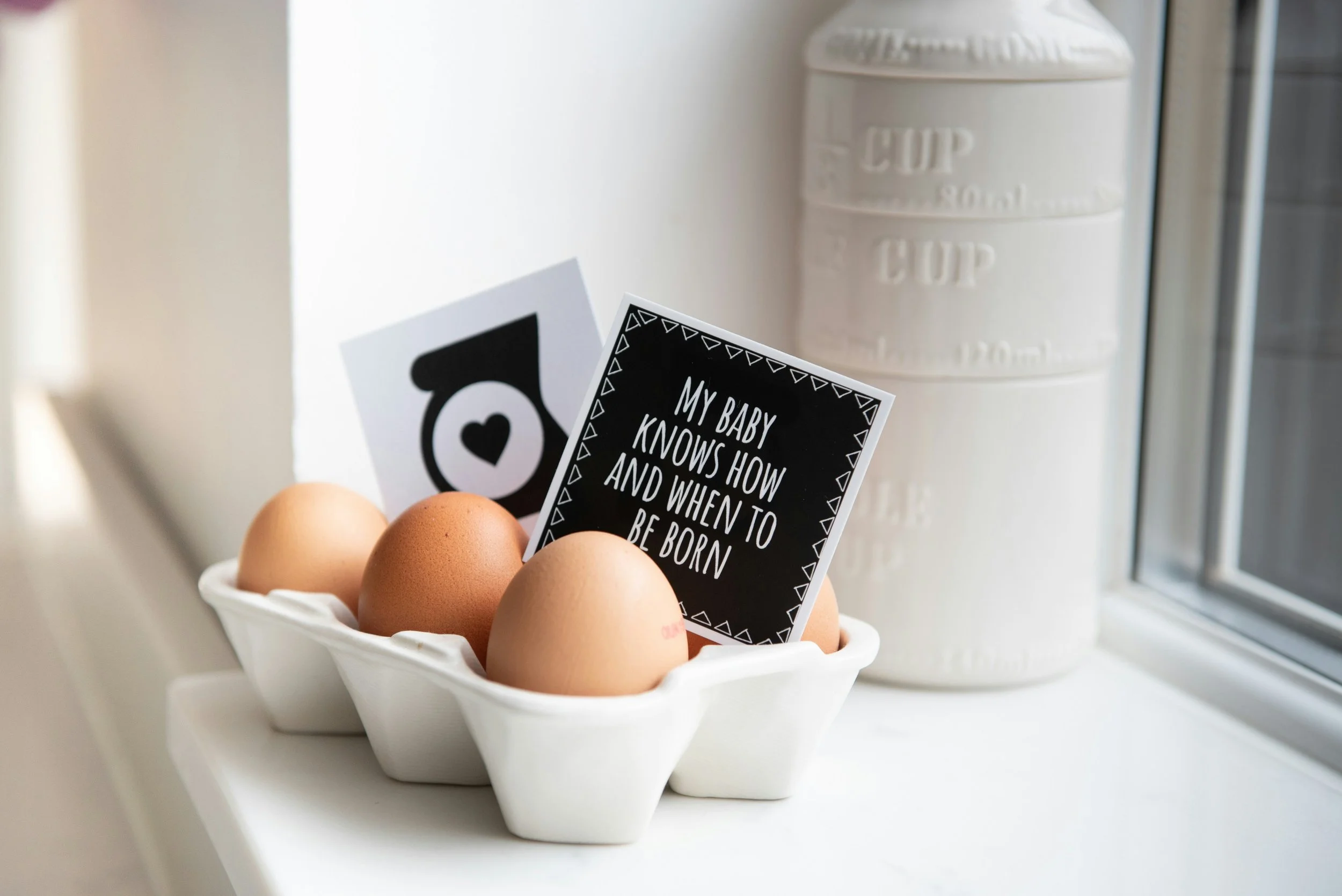 Eggs in a tray with a sign that says: my baby knows how and when to be born featured in a blog called What is Natural Birth by Grateful Heart Company