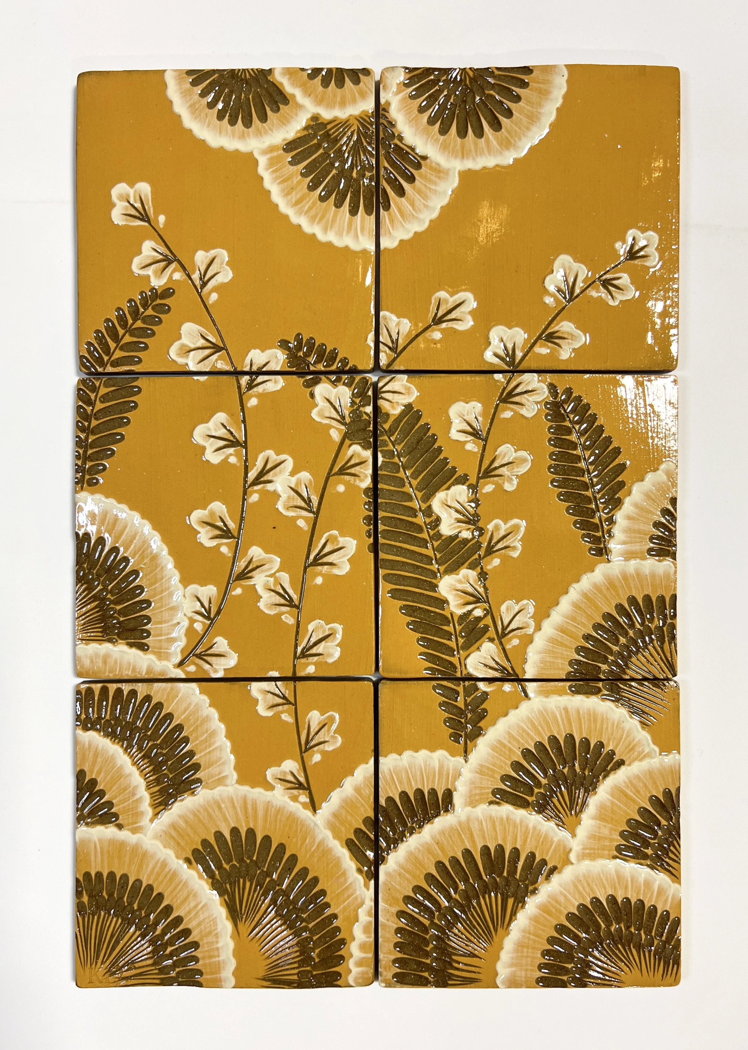 A decorative wall art piece consisting of six square tiles with a floral pattern in shades of yellow, orange, white, and brown. The pattern features stylized flowers and leaves arranged in a symmetrical design.