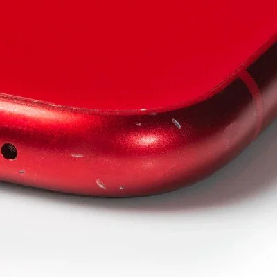 Close-up of a red electronic device with scratches and scuffs on the surface.