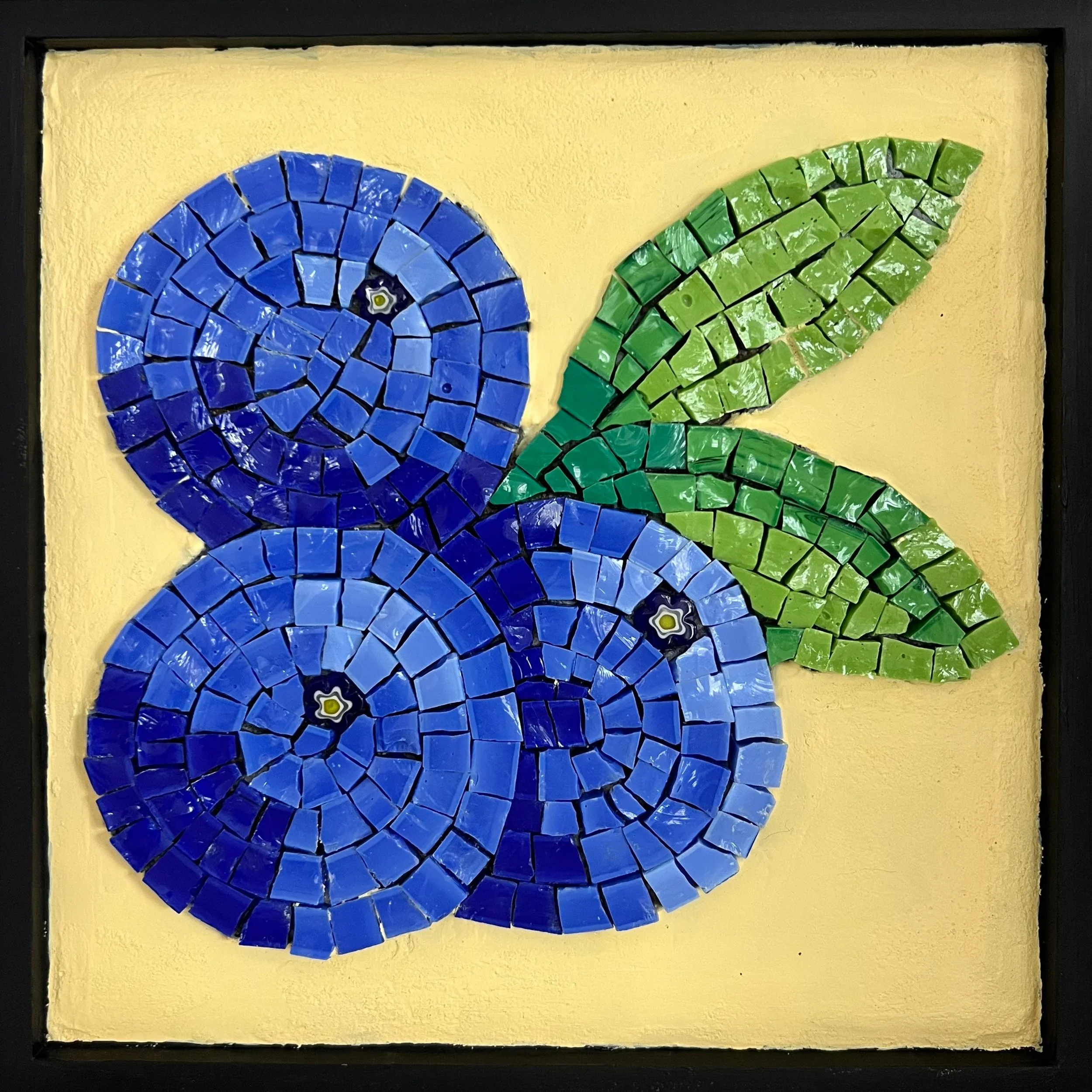 Mosaic art of three blueberries with green leaves on a yellow background.