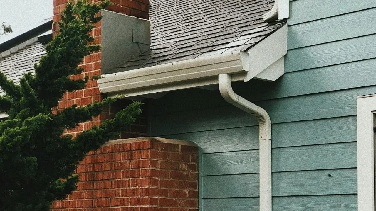 Clean roof gutter and downspout directing rainwater away from a home. 